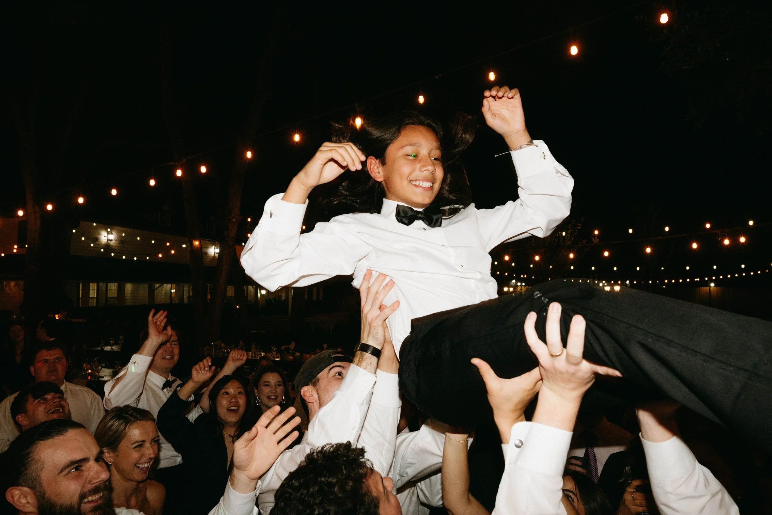 Bride's brother being tossed in the air by guests enjoying Hybrid7 and their live music at Oaktree Manor in Spring TX