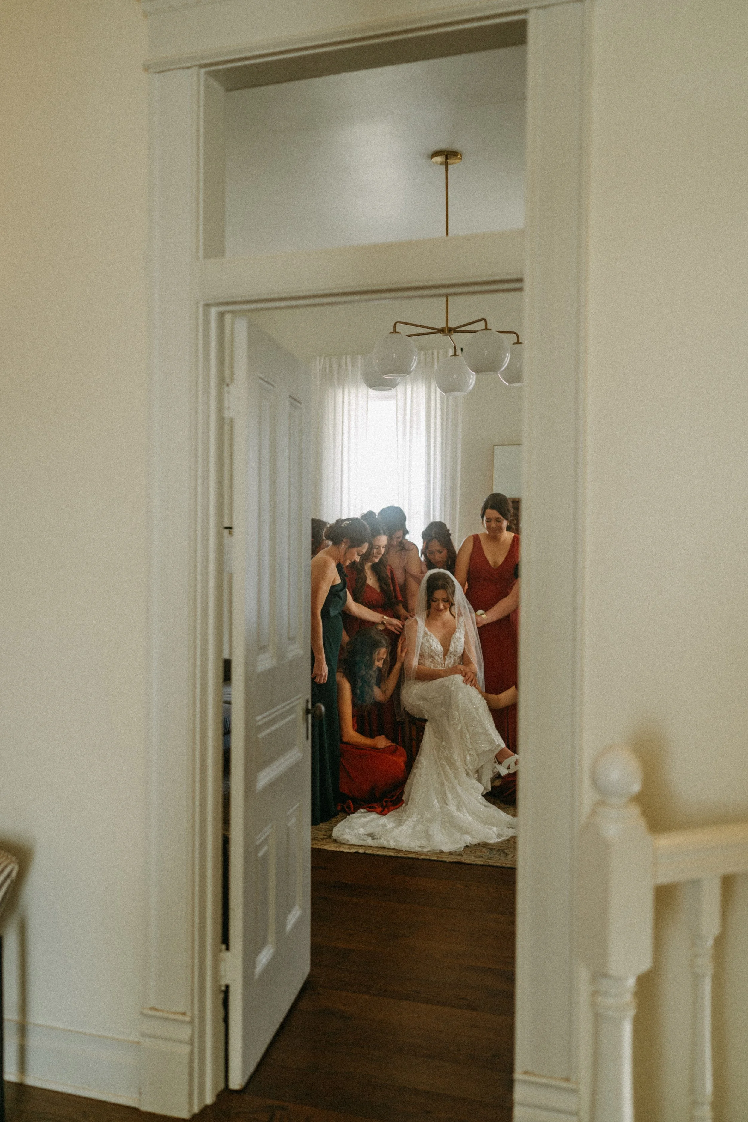 documentary style wedding photography candid of the bride being prayed over by her bridesmaids in the light airy bridal suite at The Grand Lady in manor tx just outside of austin