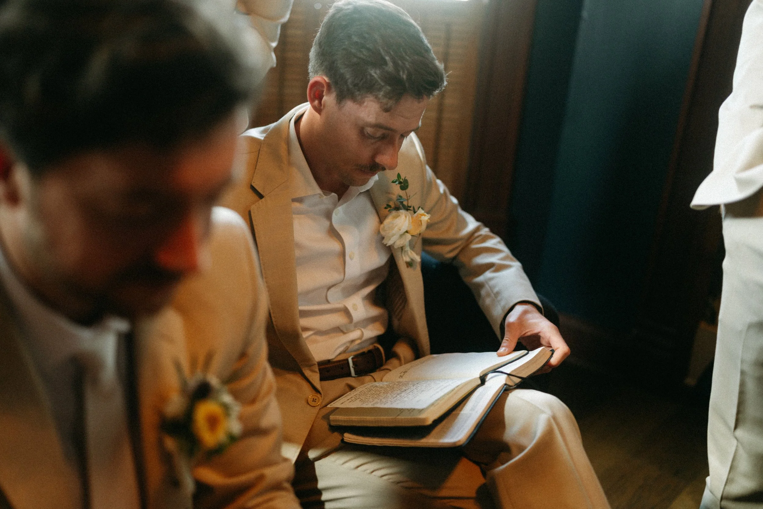 documentary style wedding photography candid of the groom being prayed over by groomsmen in the old money library at The Grand Lady in manor tx just outside of austin