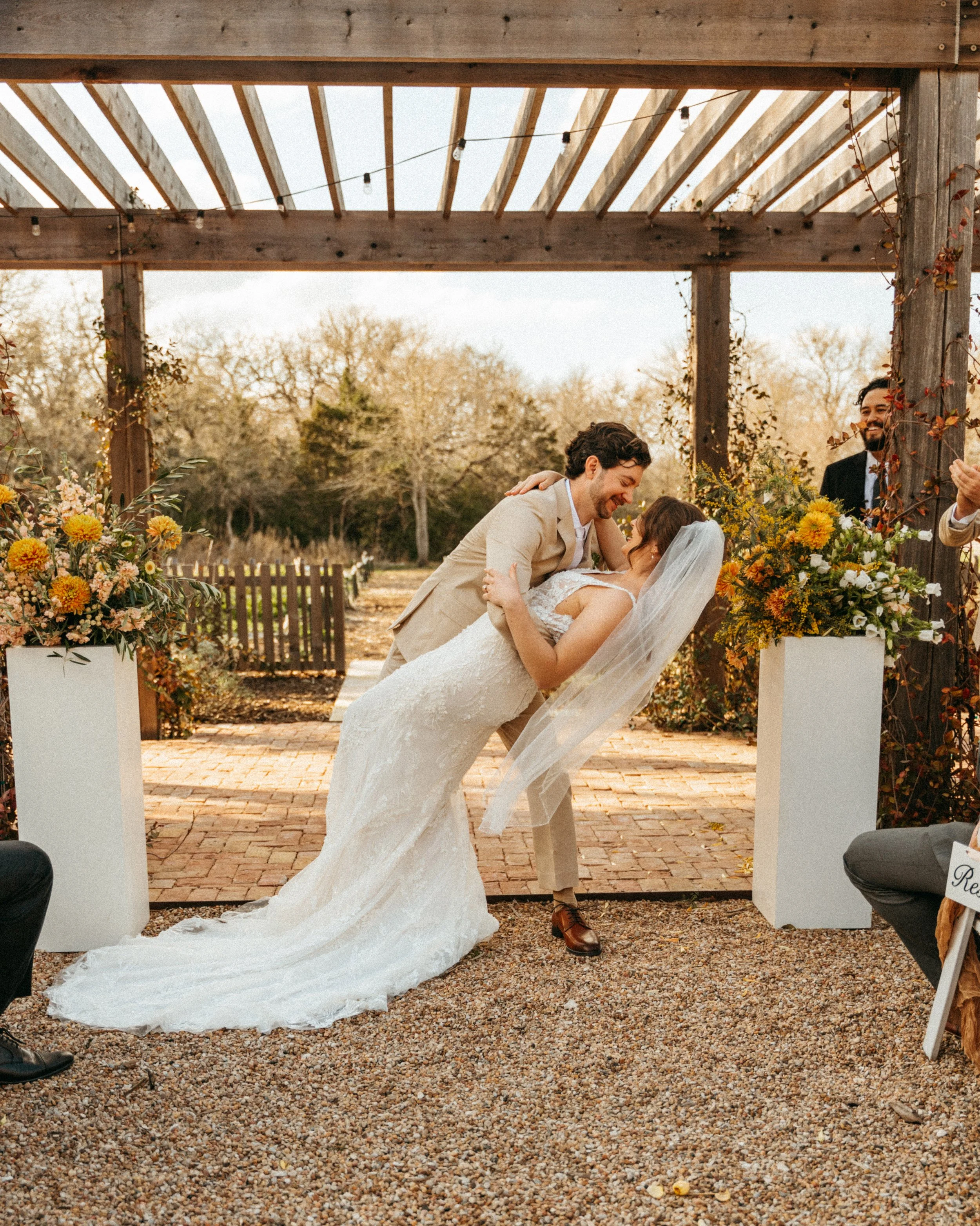 Groom dips bride to share first kiss under pergola at The Grand Lady wedding ceremony