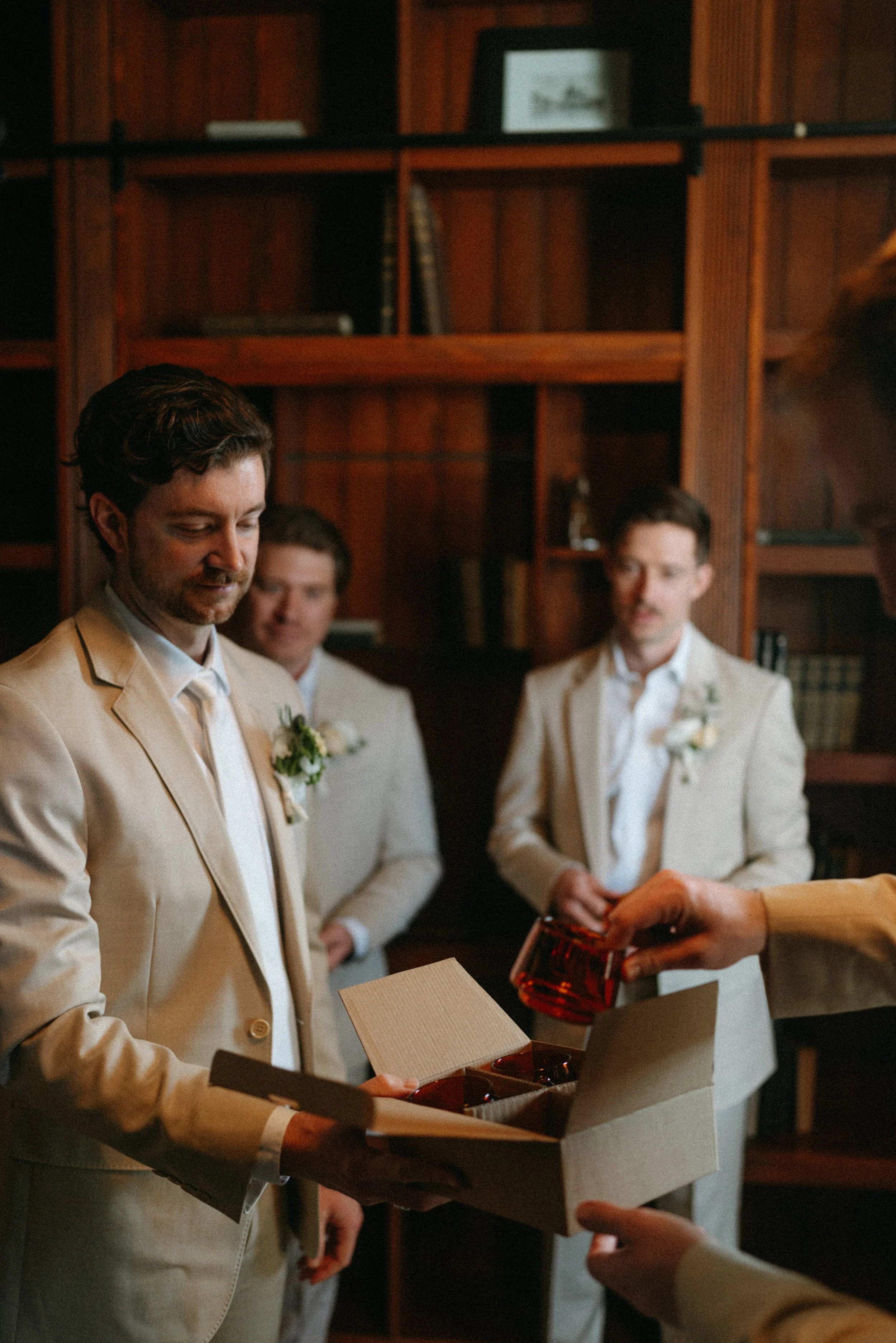 documentary style wedding photography candid of the groom and groomsmen in the old money library at The Grand Lady in manor tx just outside of austin
