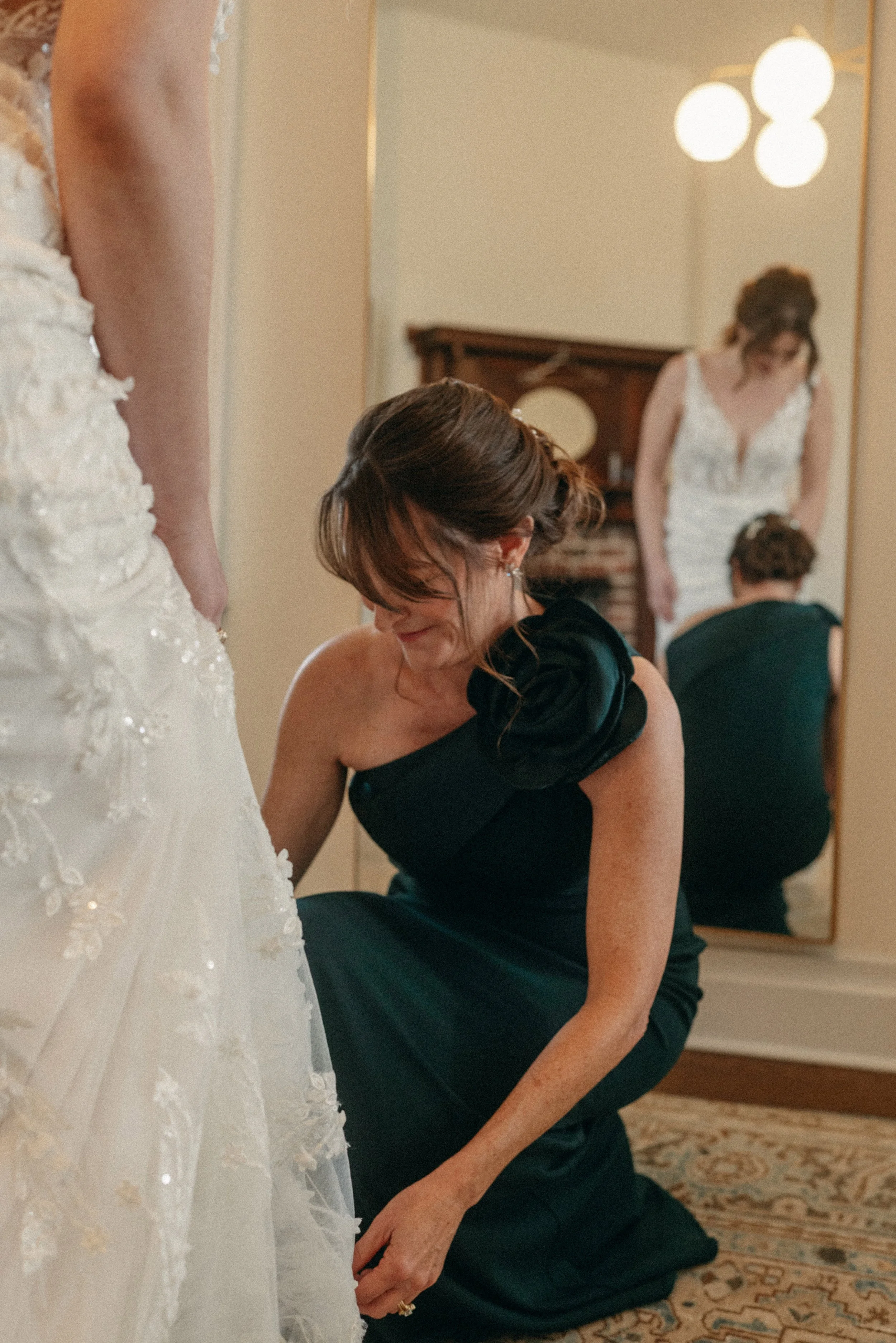 candid of Mother of the Bride getting helping bride get into her bridal gown in mansion suite at The Grand Lady in manor tx just outside of austin
