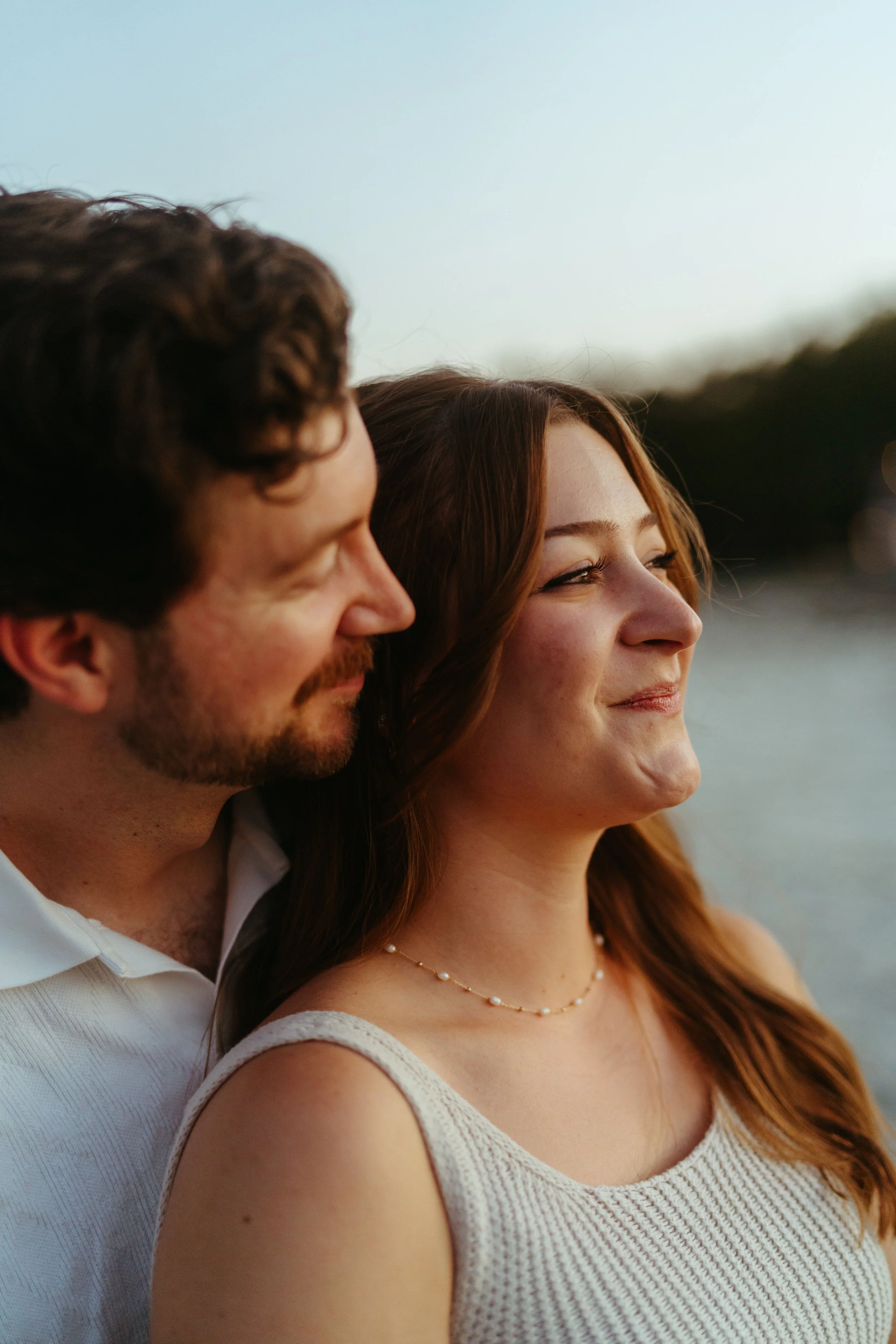 Couple sitting by the lake at sunset during Austin lake-side proposal photography session