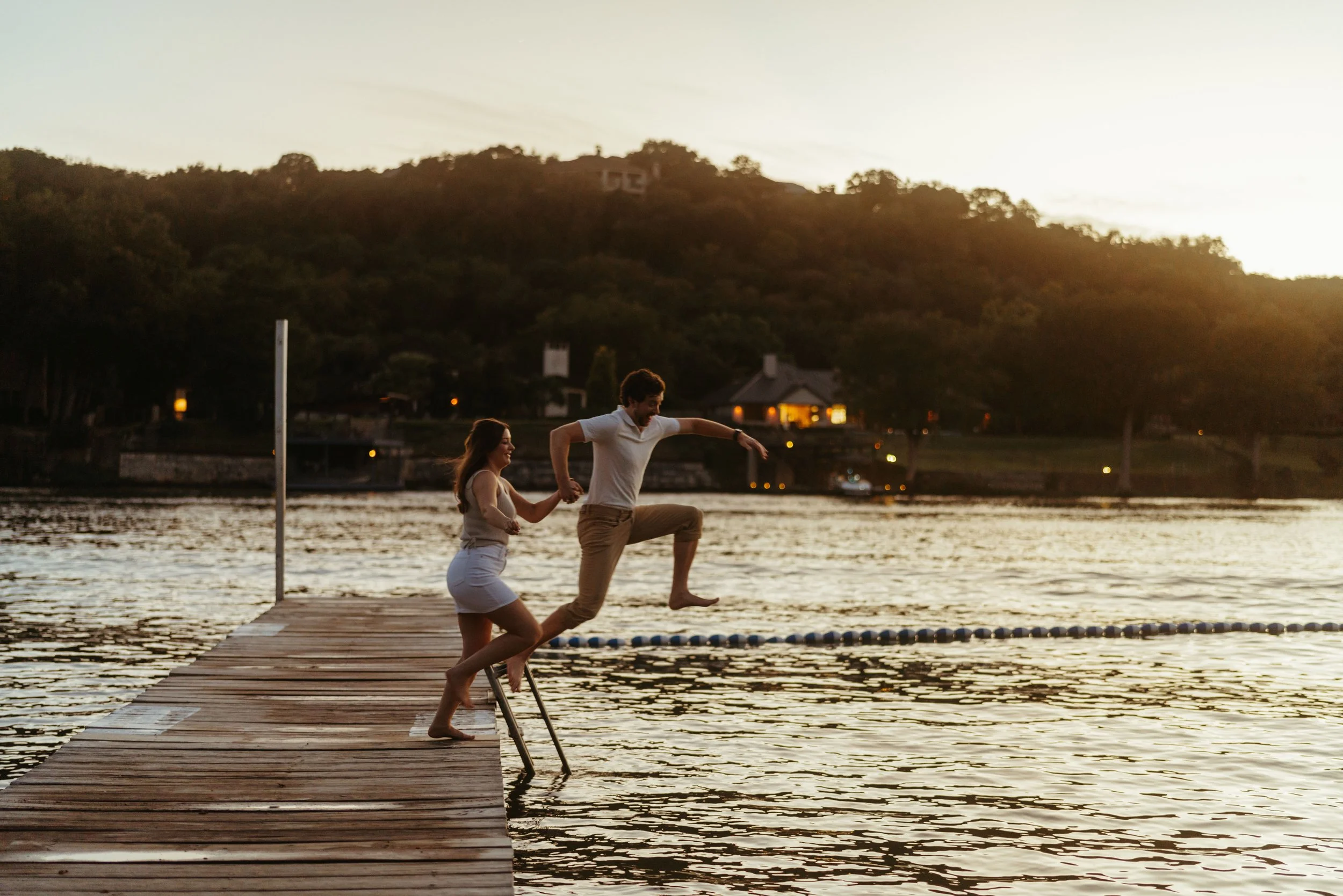 Couple jumping into lake fully dressed during Austin engagement photography session