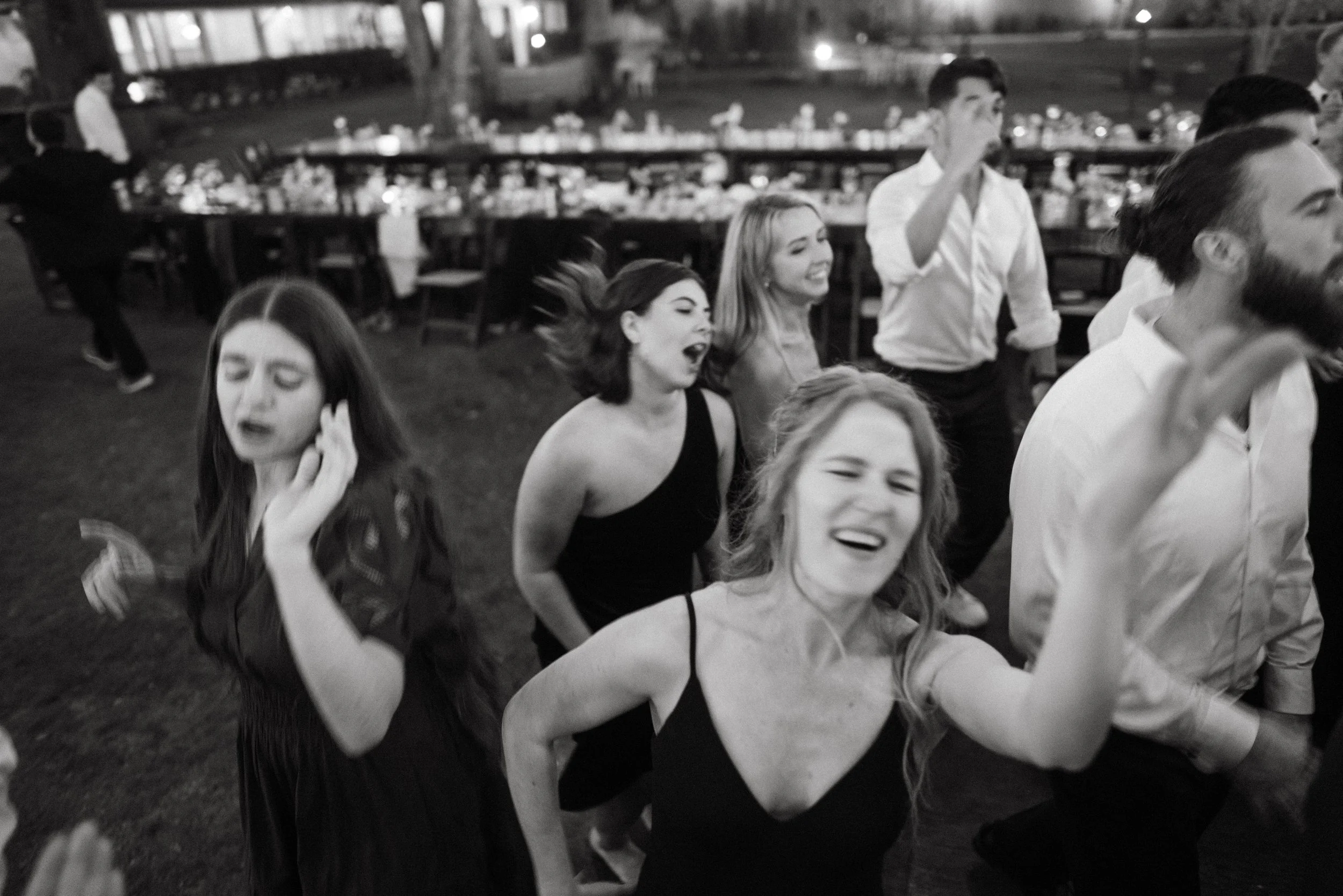 Wedding guests raising hands on the dance floor with live band playing.