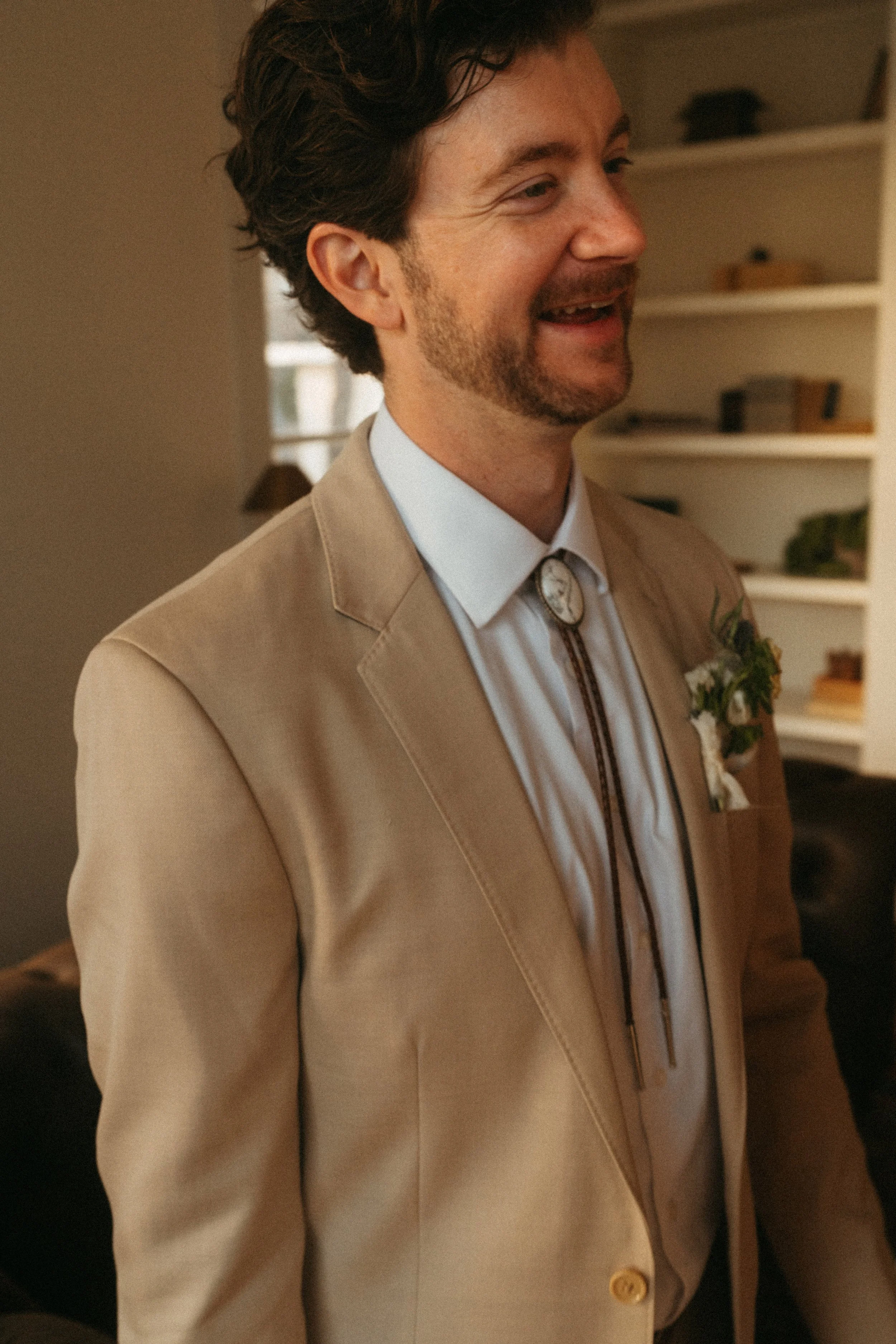 Groom trying on his bolo tie wedding gift by the grand windows at The Grand Lady in Austin