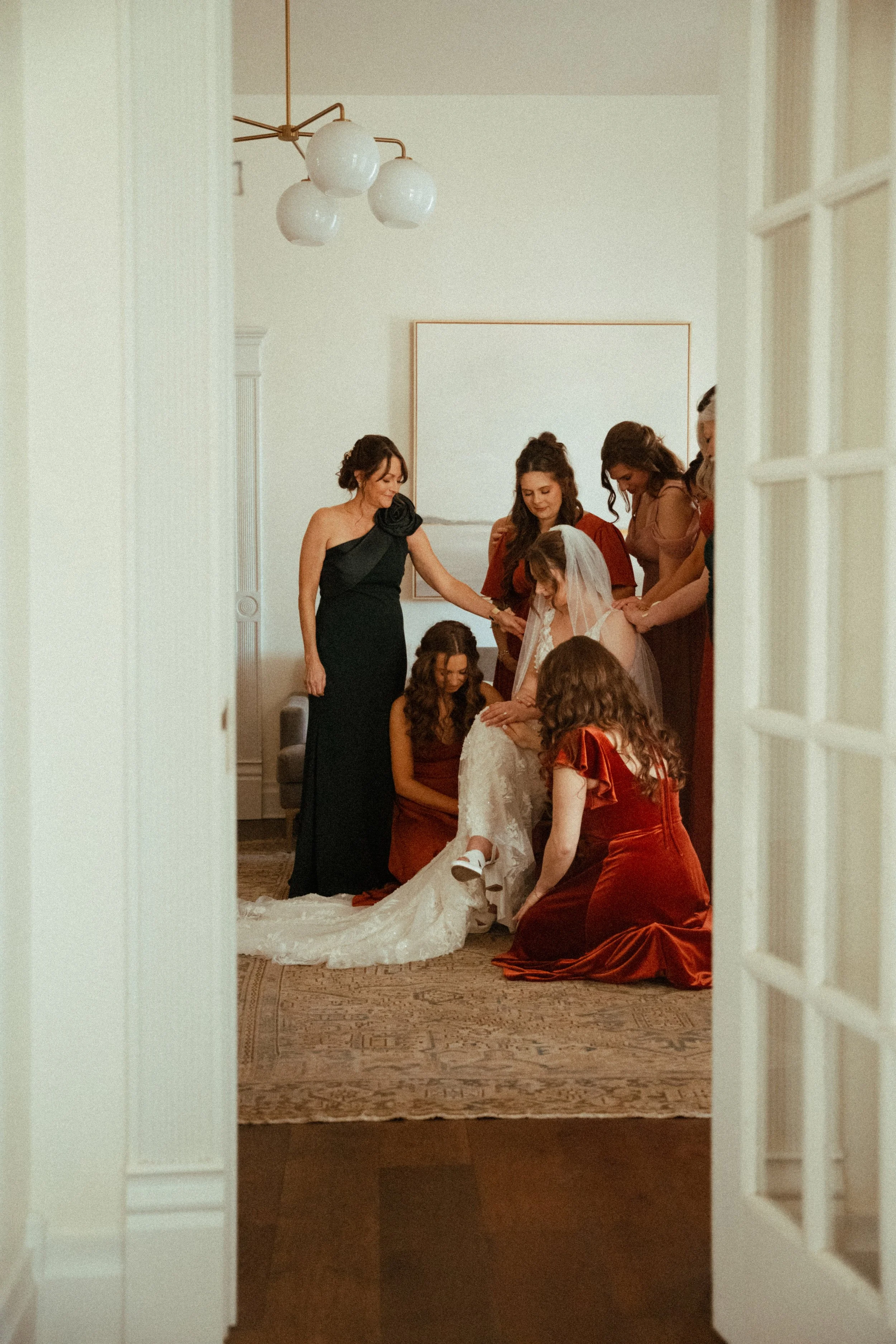 documentary style wedding photography candid of the bride being prayed over by her bridesmaids in the light airy bridal suite at The Grand Lady in manor tx just outside of austin