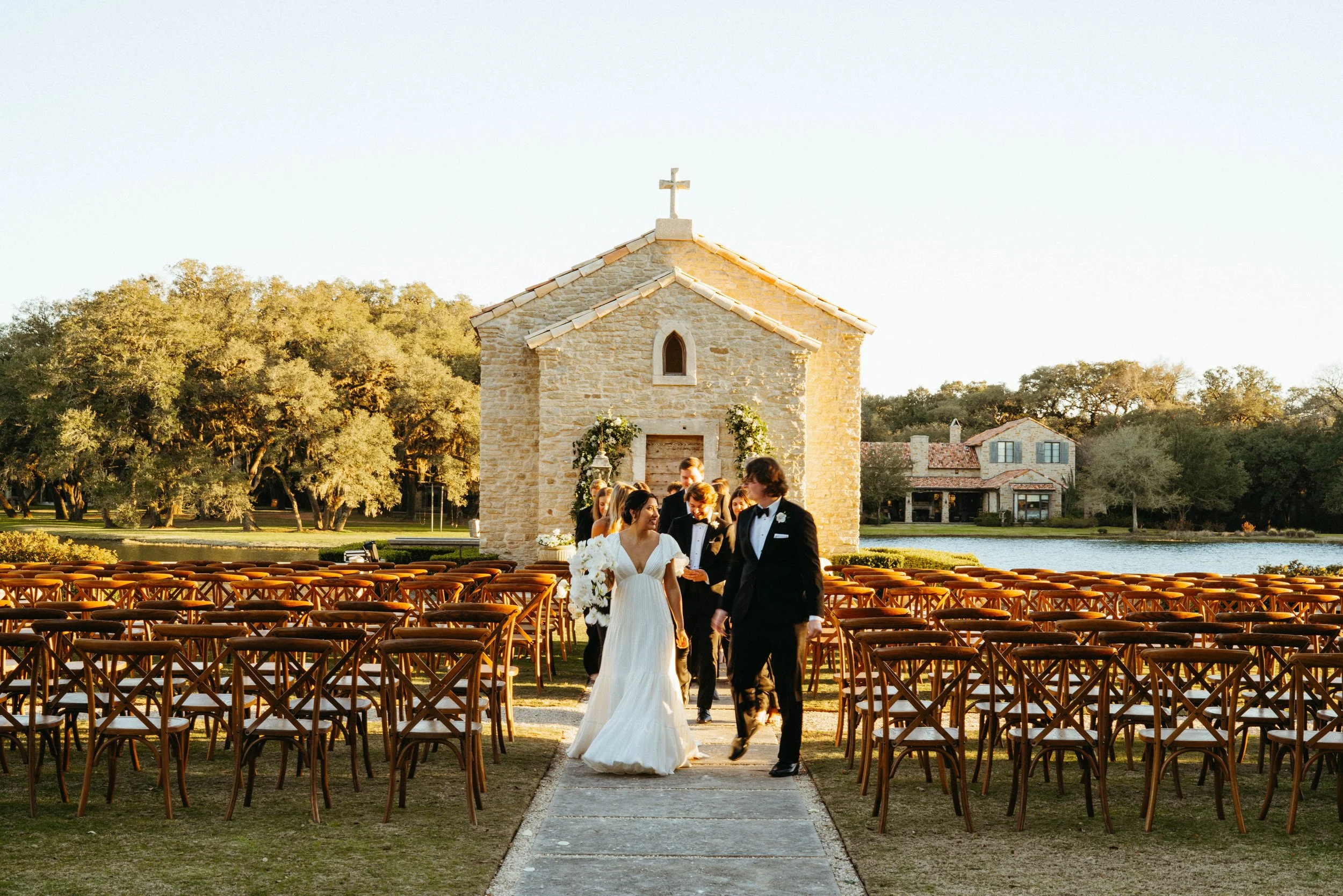 Newlyweds walking hand in hand near the historic French chapel | Austin travel wedding photographer.