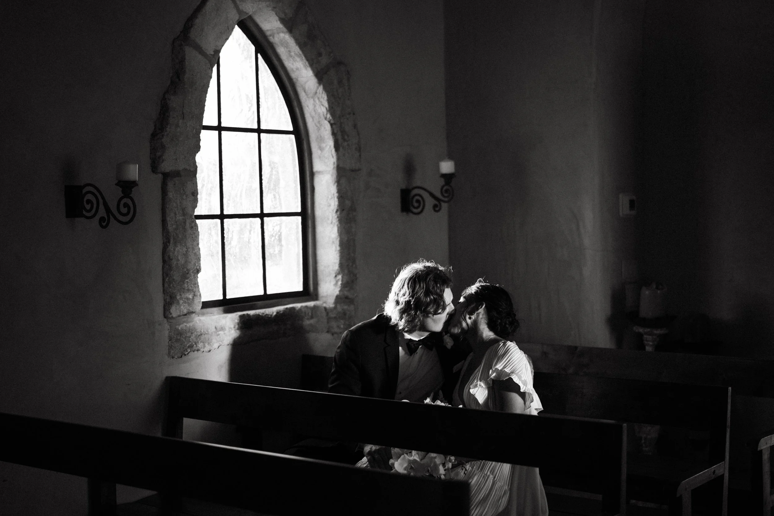 Couple sharing a kiss in the 17th-century French chapel at Houston Oaks.
