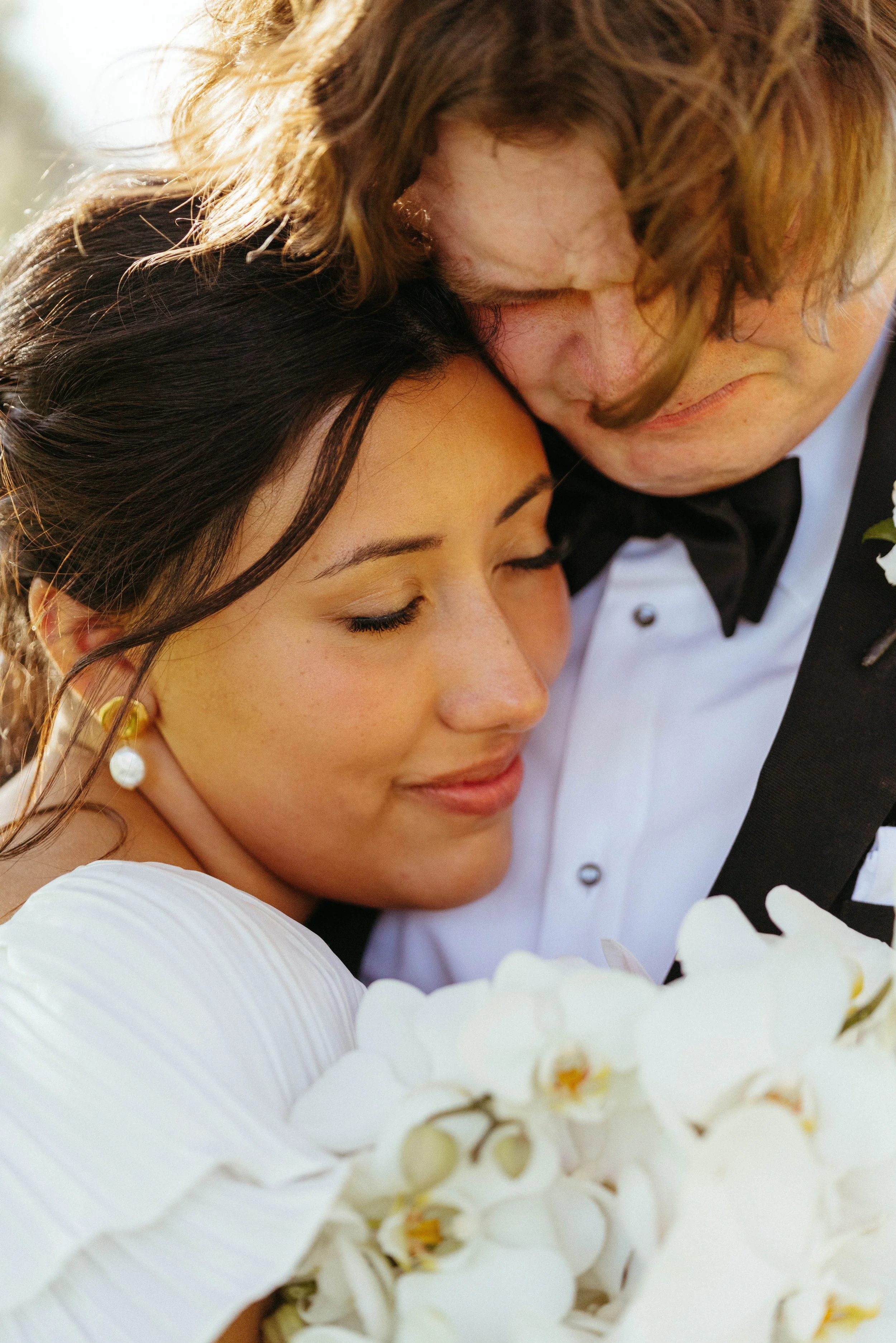 Bride resting her head on groom’s shoulder during portraits at Houston Oaks.