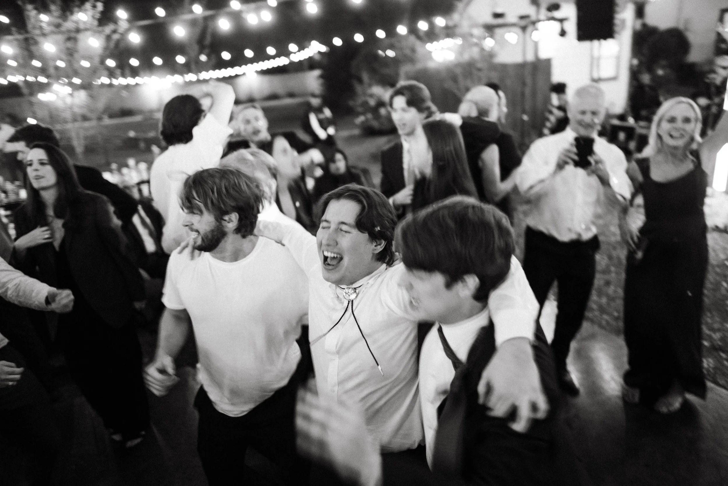 High-energy candid moment with groomsmen and friends dancing at Oaktree Manor reception