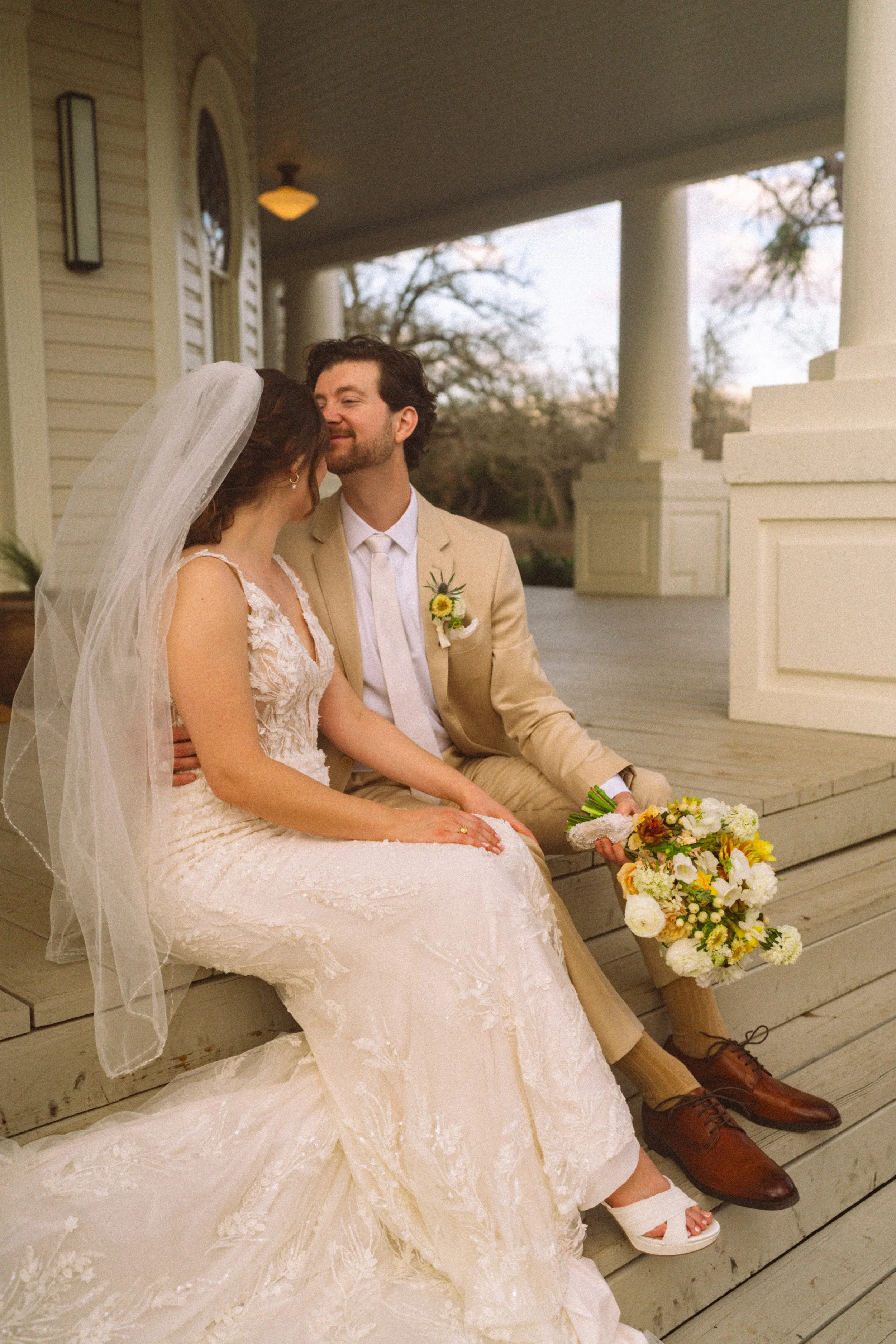 Bride and groom kissing in front of The Grand Lady historic mansion