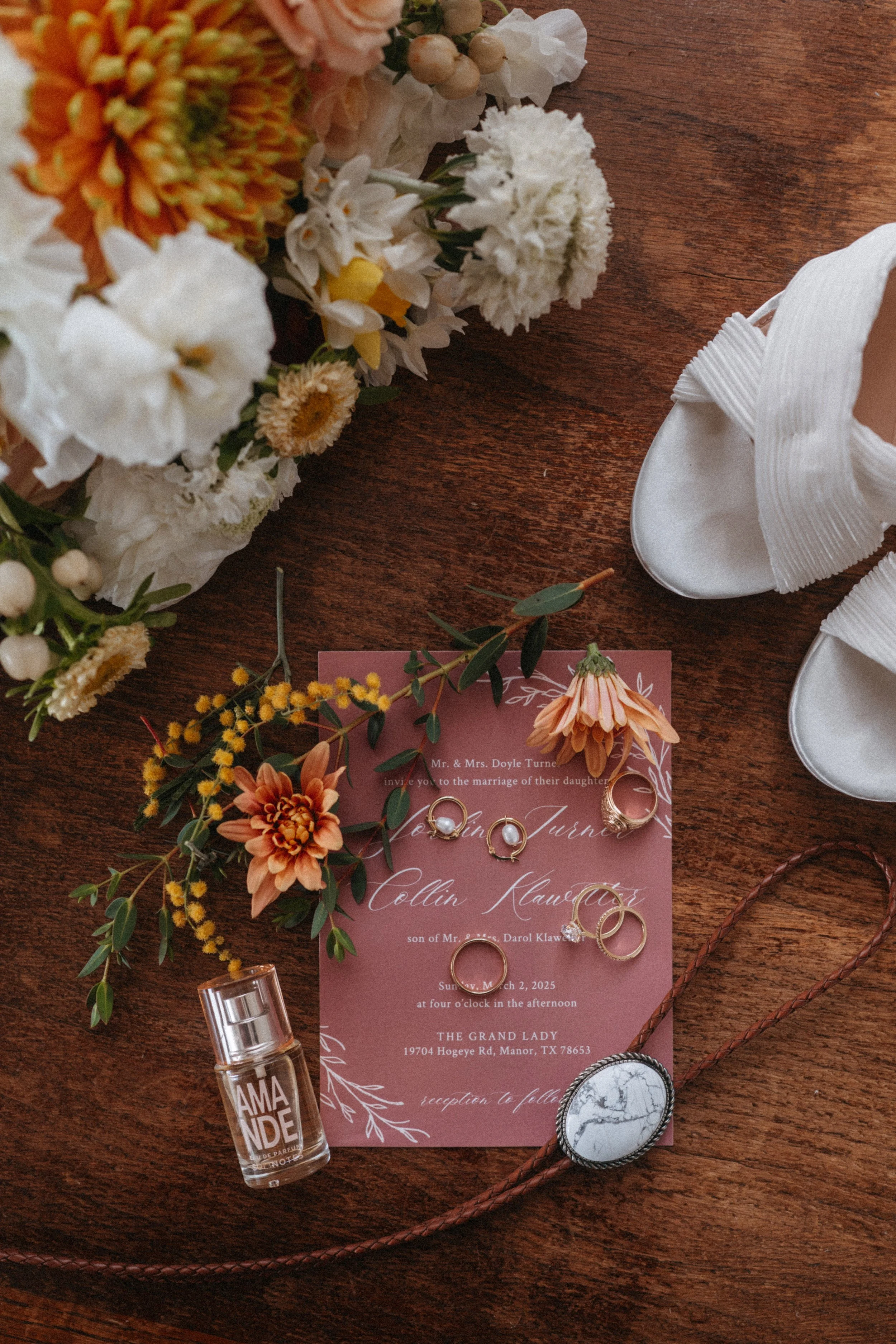 Flatlay of wedding invitations with florals, jewelry, and wedding shoes at The Grand Lady Austin wedding