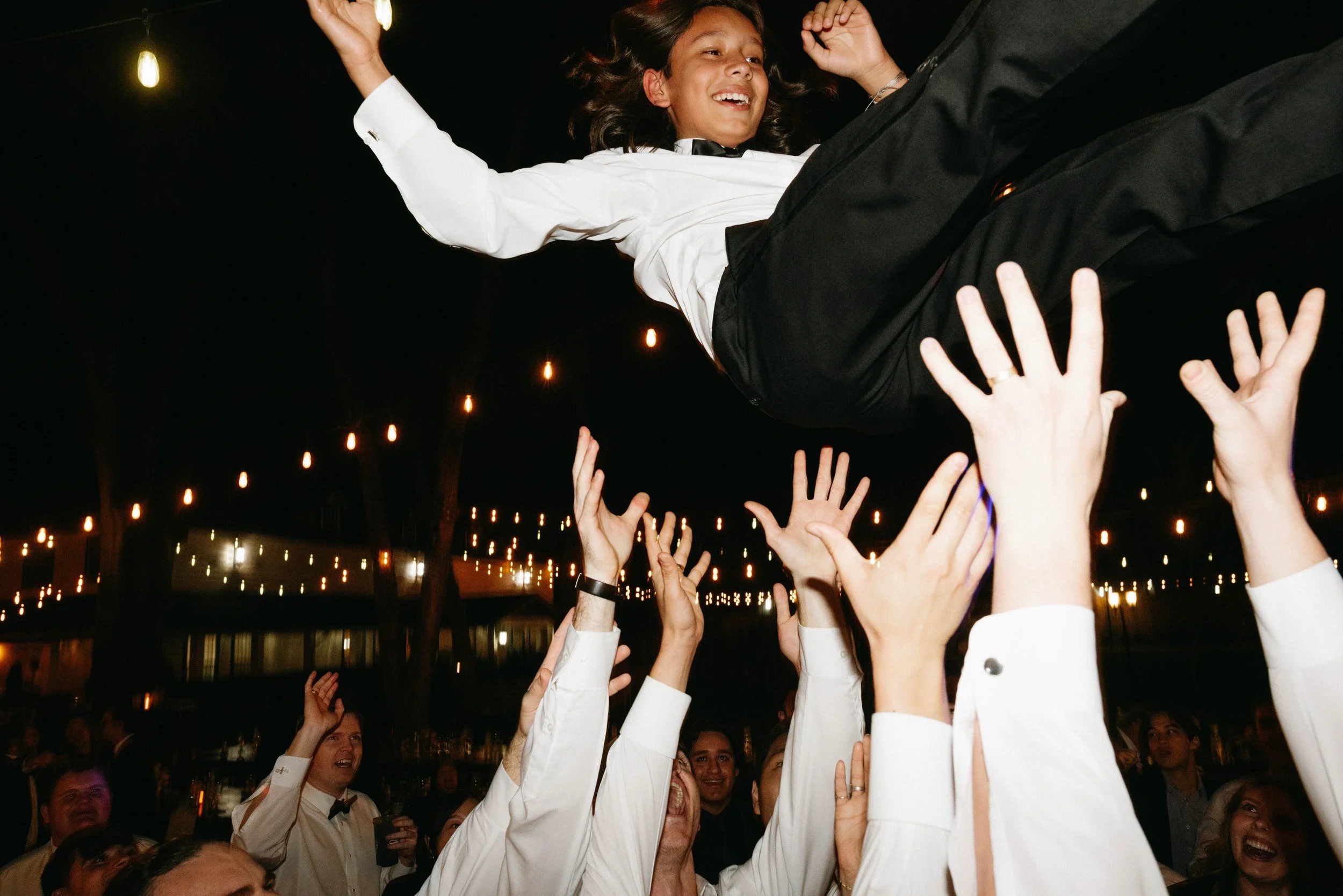 Bride's brother being tossed in the air by guests enjoying Hybrid7 and their live music at Oaktree Manor in Spring TX