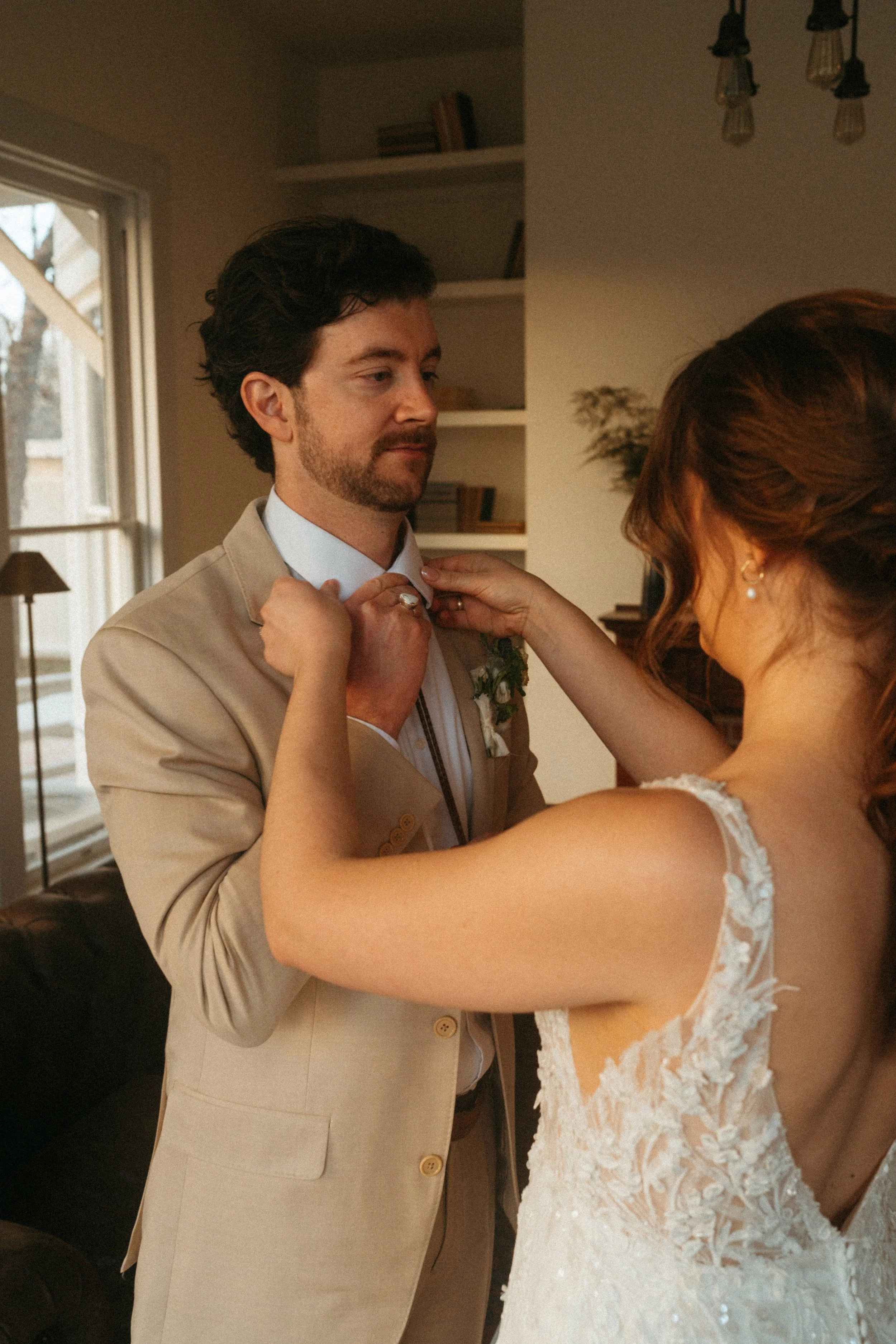 Groom trying on his bolo tie wedding gift by the grand windows at The Grand Lady in Austin