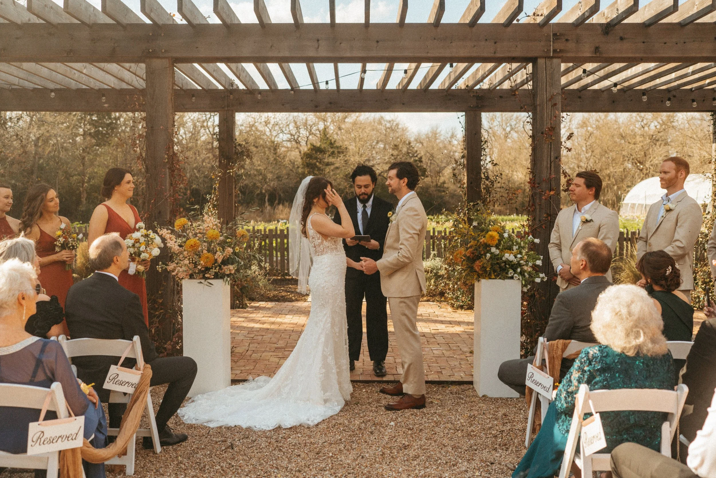 Bride and groom exchange vows under the pergola in The Grand Lady flower garden in Manor, TX