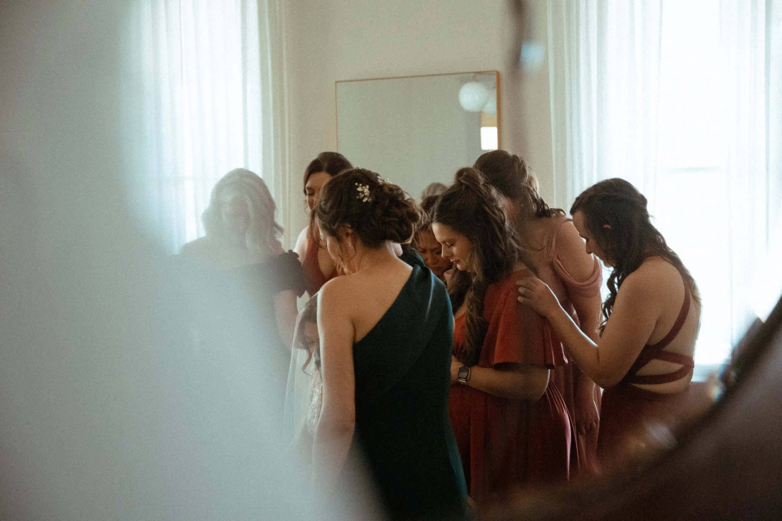 non-traditional candid of the bride being prayed over by her bridesmaids in the light airy bridal suite at The Grand Lady in manor tx just outside of austin
