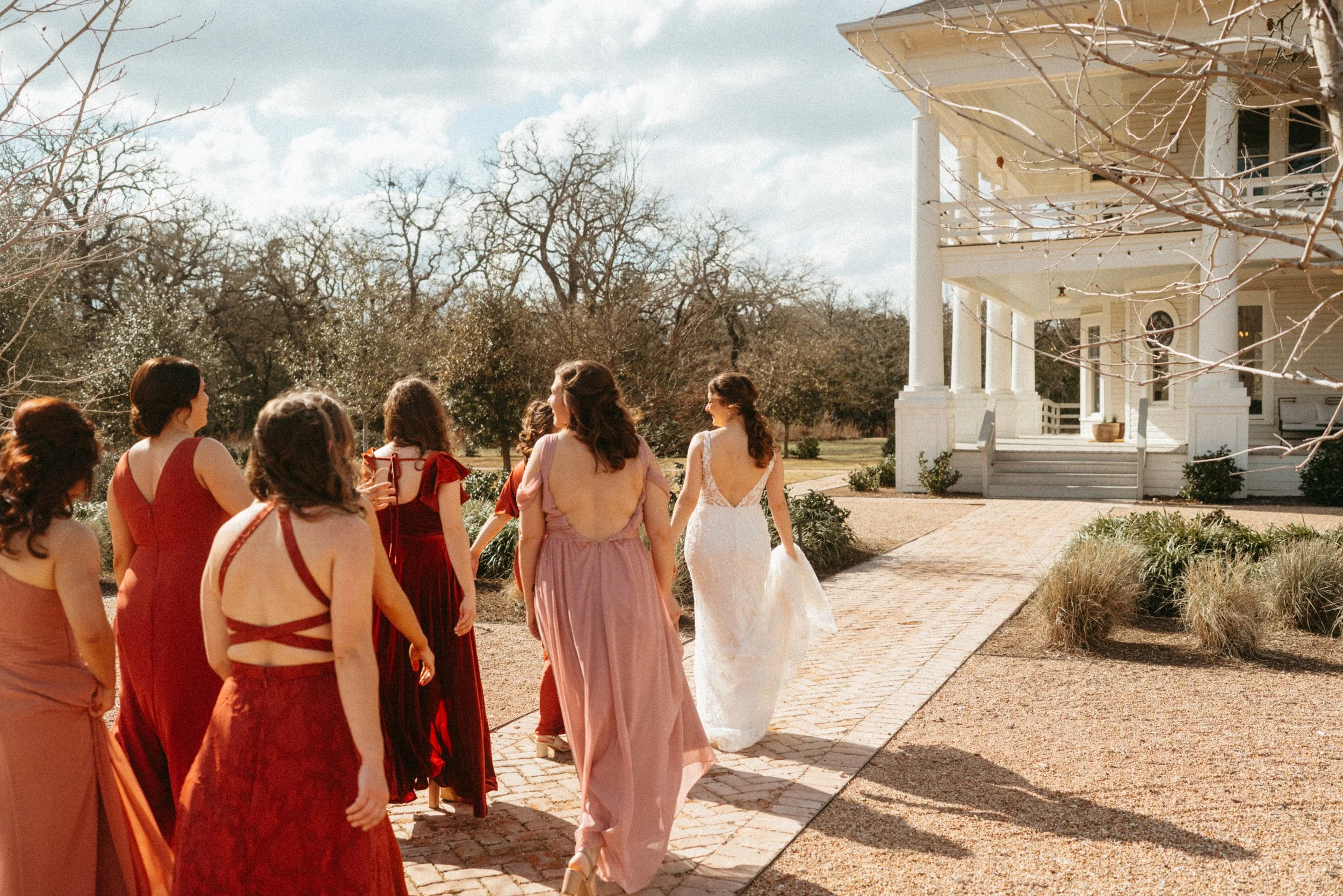 Bridesmaids walking to the grand lady mansion in beautiful red bridesmaids dresses at The Grand Lady Austin wedding