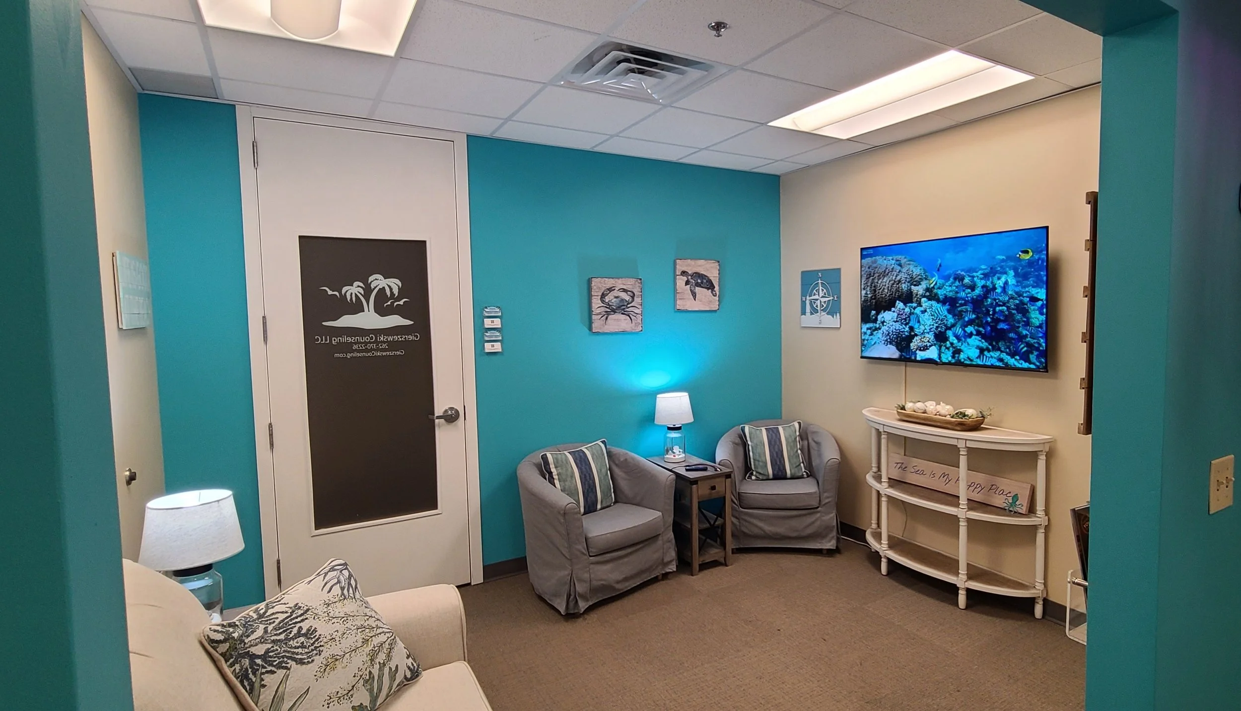 A secondary view of the calming beach-themed lobby at Gierszewski Counseling LLC, showcasing comfortable armchairs and the office entry door.