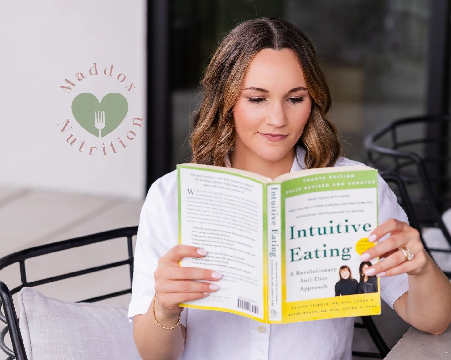 A woman reading the 'Intuitive Eating' book, illustrating the journey into learning 'Intuitive Eating: What It Is and the 10 Principles