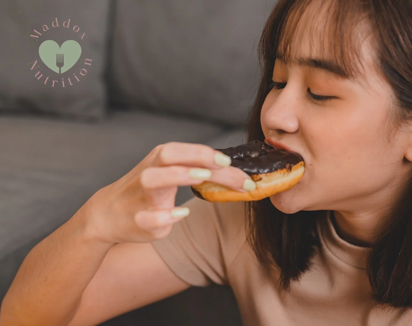 A woman enjoying a chocolate donut, showing how she improved her relationship with food.