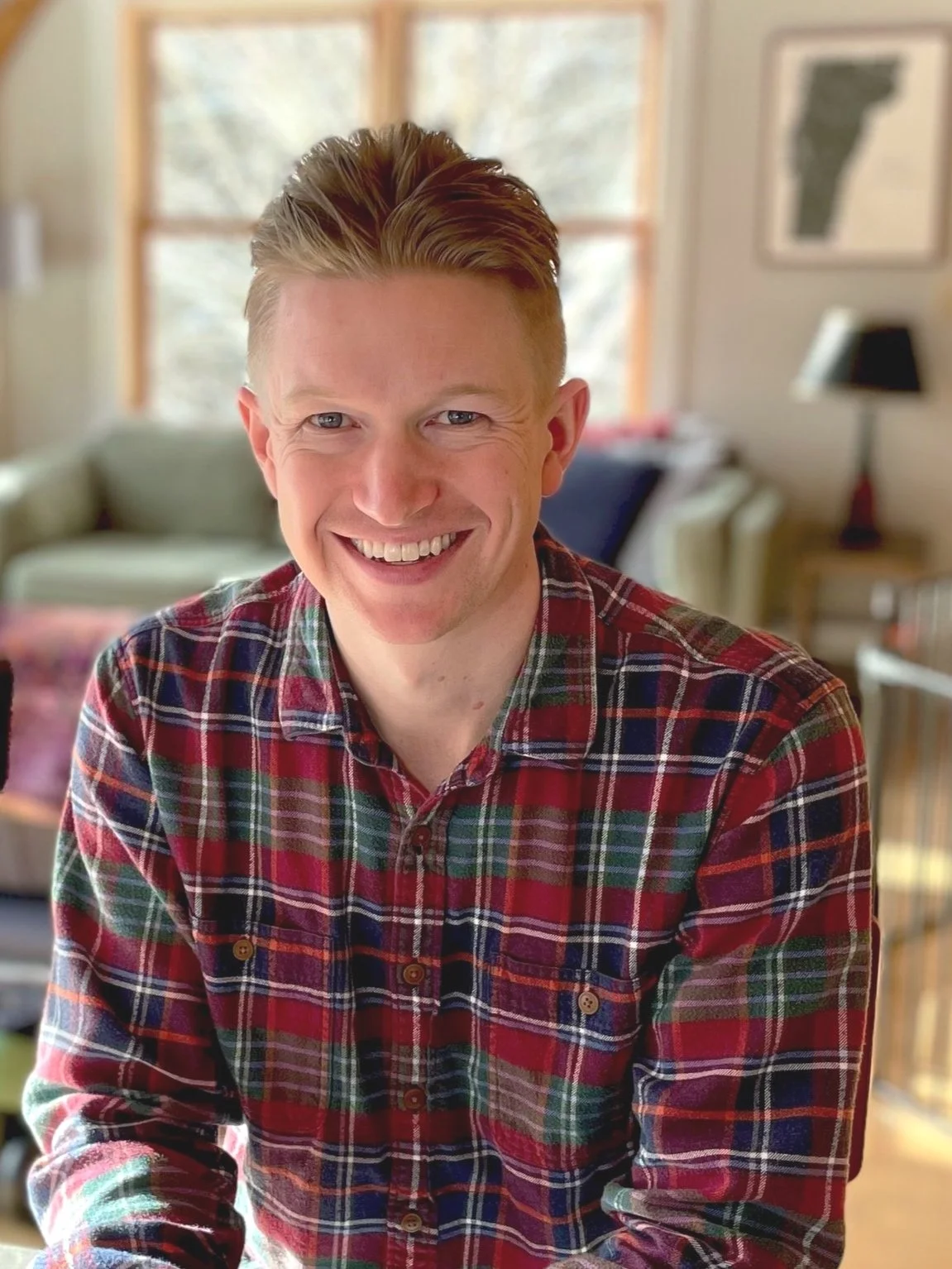 Andrew Herwig, Personal Finance and Business Coach, smiling in a warmly lit home environment