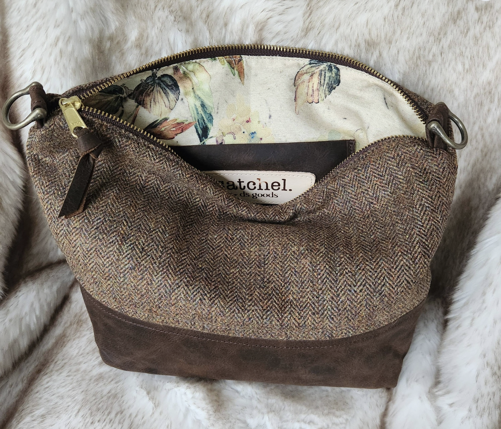 The inside of a floral-patterned fabric bag with a zipper pocket and a label that reads 'Satchel'.