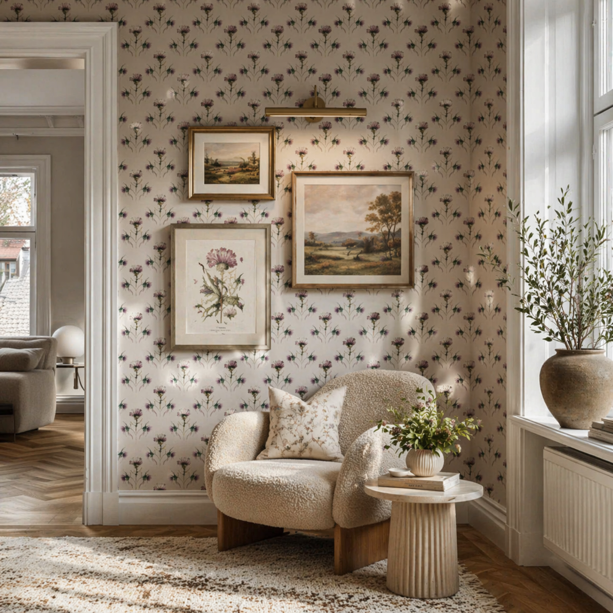 Interior of a room with floral wallpaper, a tan leather chair, and a small side table with a round cushion. A black vase is on the window sill, and part of the adjacent room with a sofa and lamp is visible.