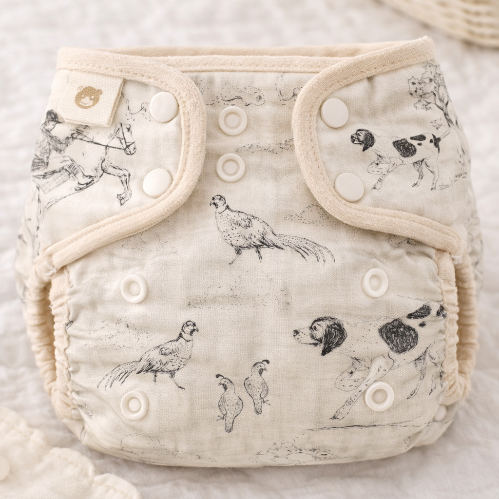 Cloth diaper with a woodland animal print featuring foxes, dogs, owls, and birds, with snap closures.