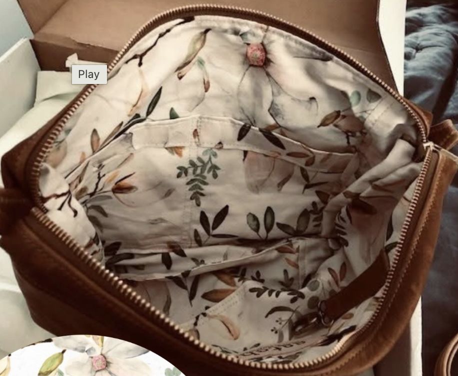 Open brown leather bag with floral-patterned fabric lining inside.