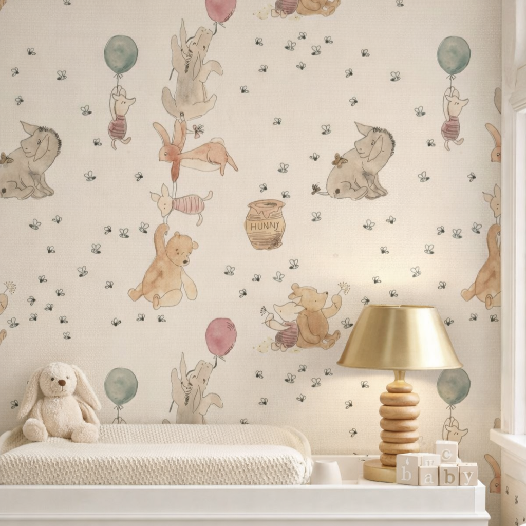 Children's wallpaper with illustrations of woodland animals, including bears, rabbits, and sheep, holding balloons and surrounded by small bees. A plush bunny toy sits on a white textured changing table, next to a gold lamp and children's blocks.