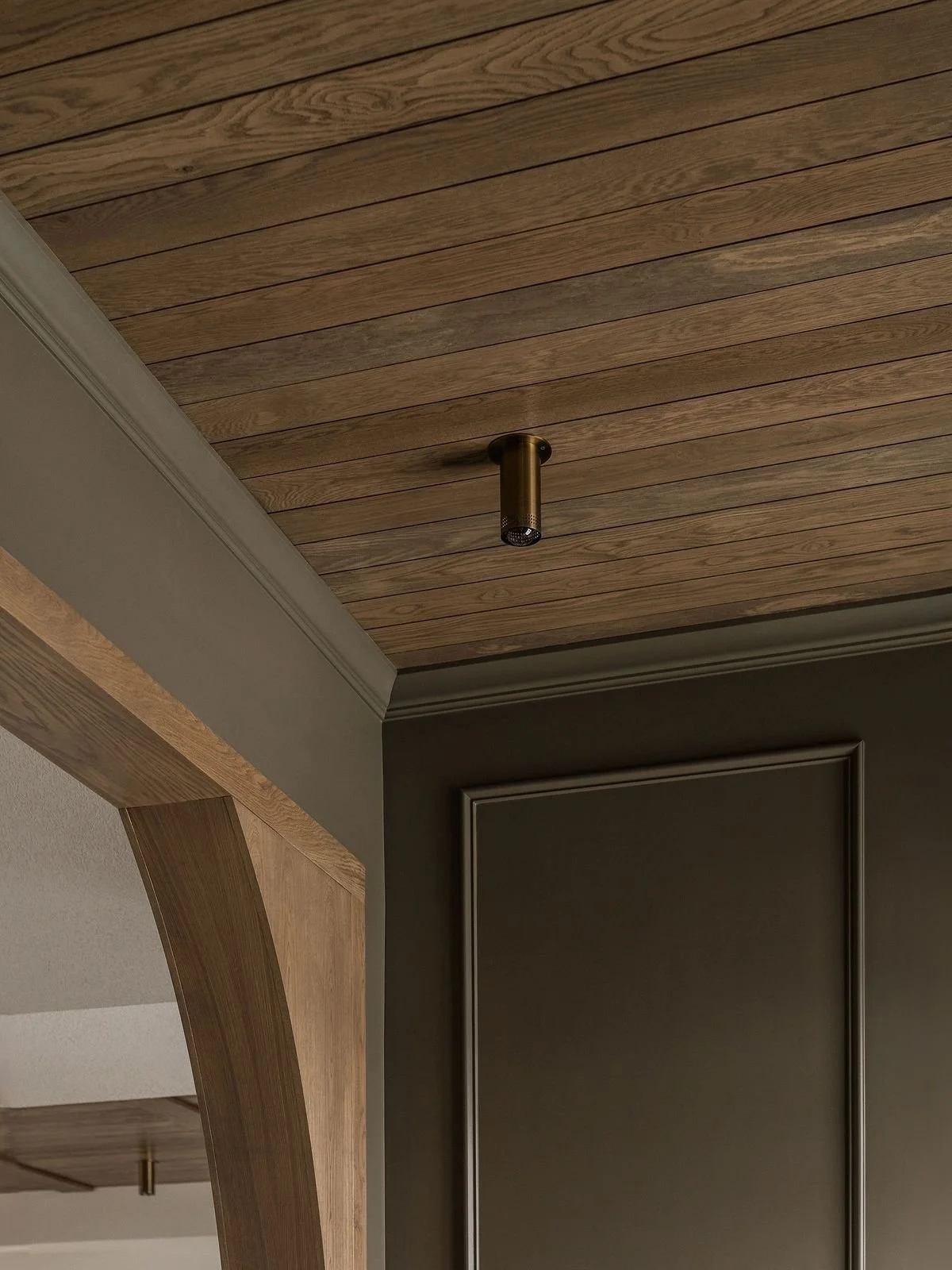 warm mid toned wood paneled ceiling, tongue and groove wood ceiling, brass ceiling mounted spotlight, arched walkway with corbel detail, add wood to your home, modern traditional mountain home