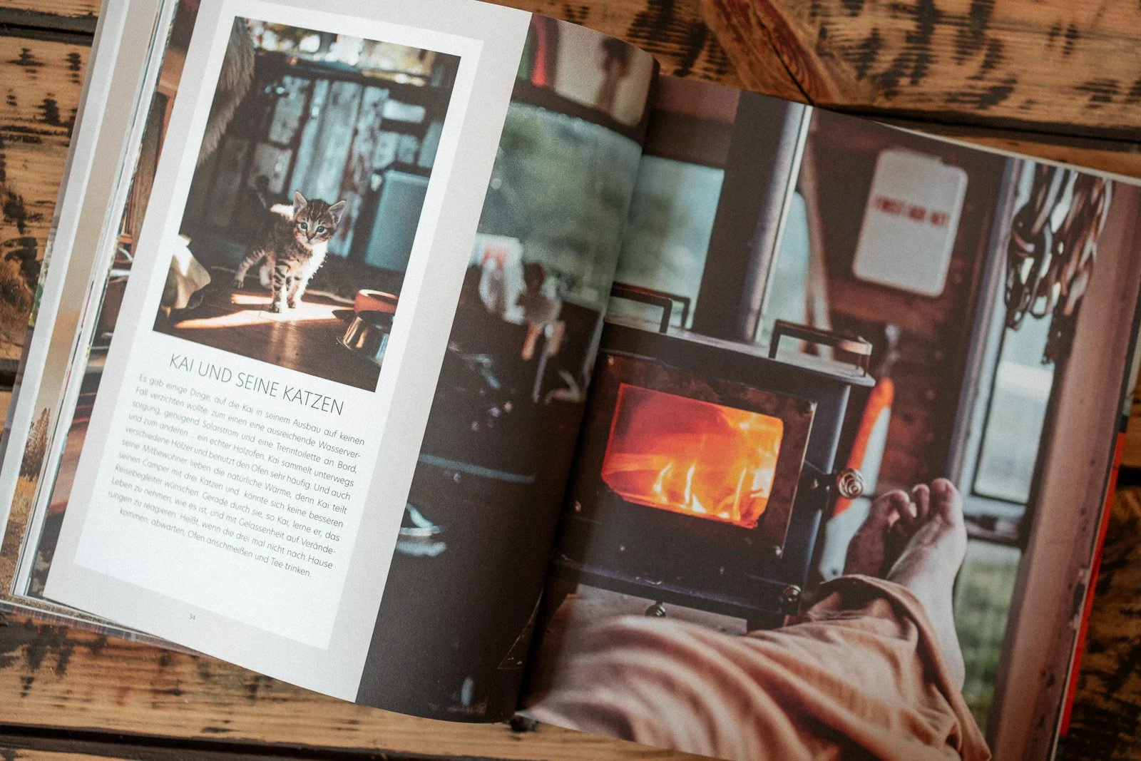 Buchseite mit einem Bild eines kleinen Kätzchens auf einem Holzfußboden und einem Küchen- oder Wohnzimmerhintergrund. Der Text darunter lautet in Deutsch: 'Kai und seine Katzen'.