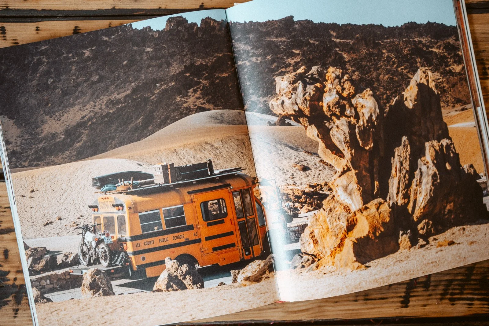 Eine gelbe Schulbus, der auf einer Wüstenlandschaft mit Felsen steht, neben einem Fahrrad.