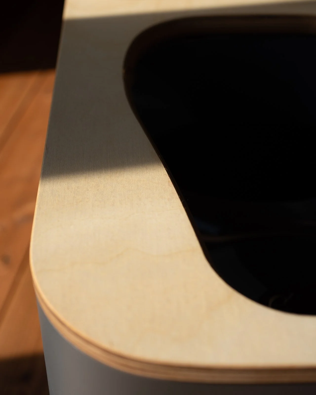 Nahaufnahme eines schwarzen Klaviers auf einer weißen Tischfläche mit Holzoptik.