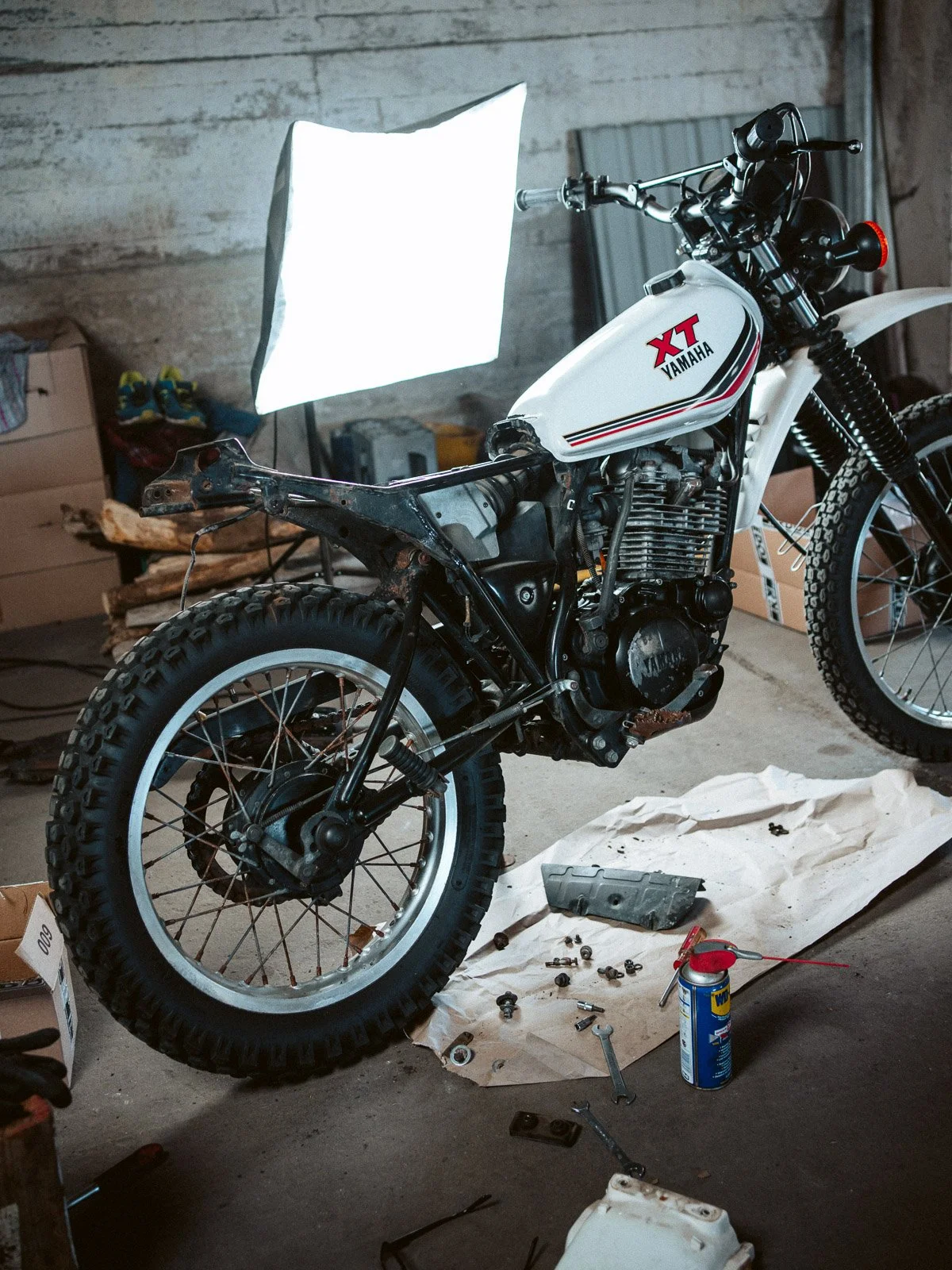 Eine Yamaha XT Motorrad im Umbau, auf einer Werkbank mit Werkzeugen und Zylindern, in einer Garage