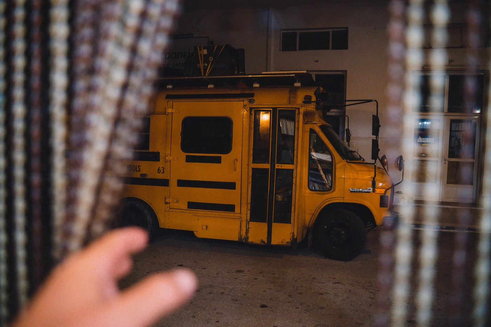 Ein gelber Schulbus, gesehen durch eine Lücke zwischen zwei Vorhängen, bei Nacht.