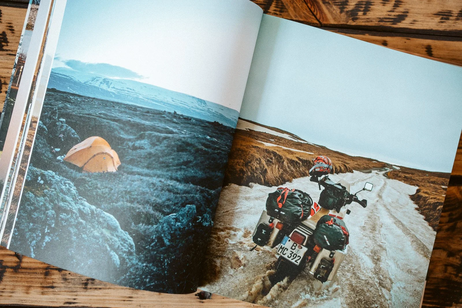 Motorrad mit Gepäck, auf einer schneebedeckten Straße in einer kargen Landschaft, im Hintergrund flaches Gelände mit Wasser und Himmel