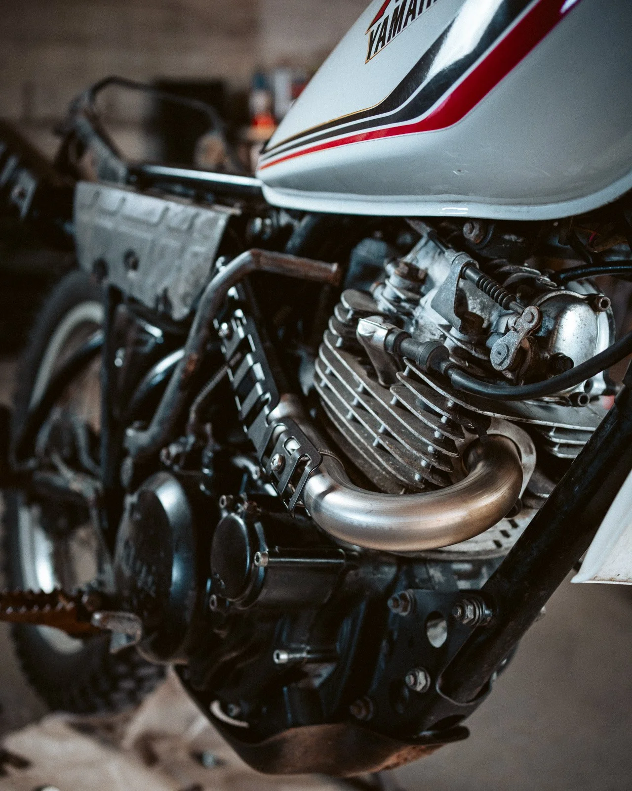 Nahaufnahme eines Motorblocks eines Motorrads mit sichtbarem Auspuff und Rahmen.