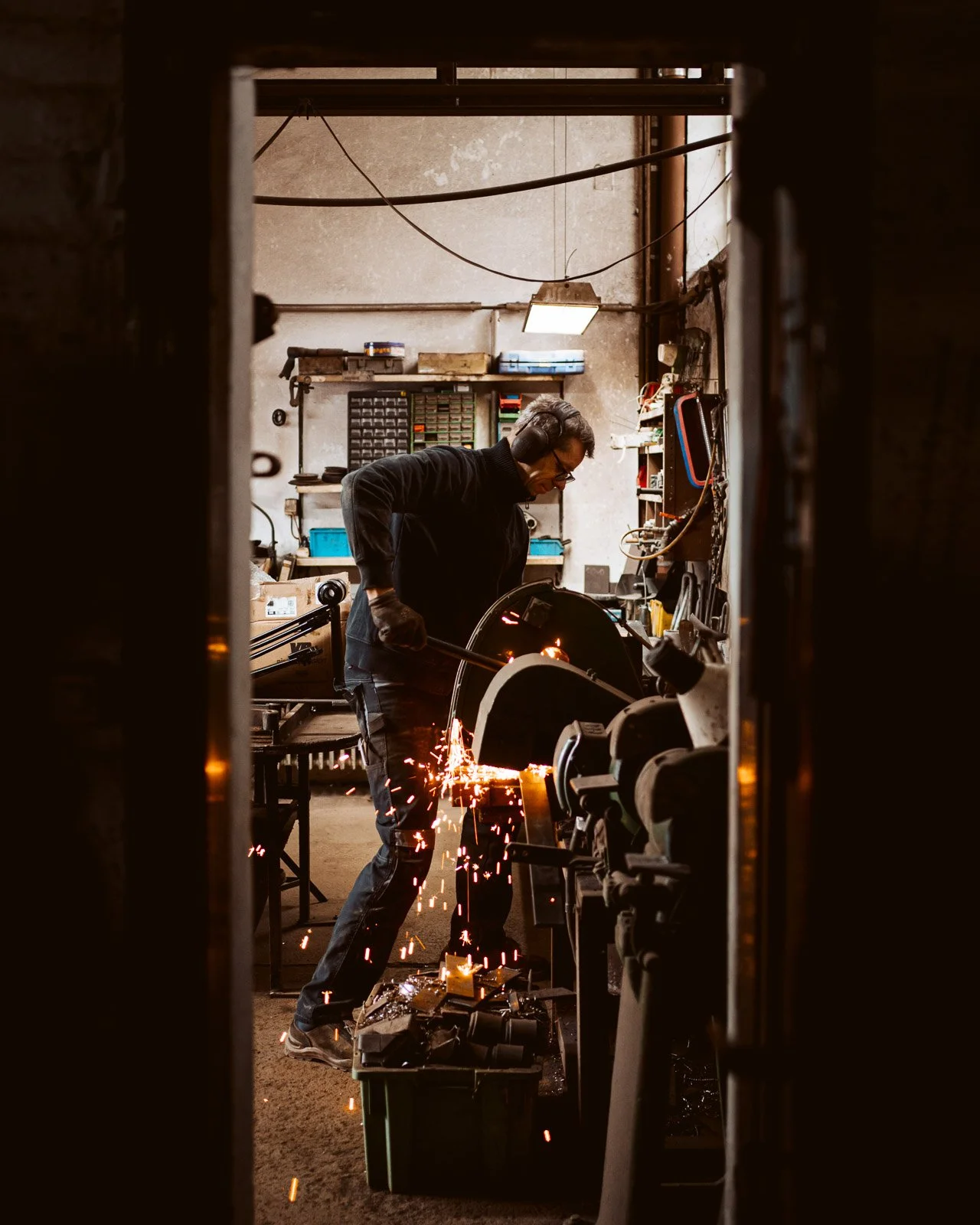 Ein Handwerker schweißt Metall in einer Werkstatt, Funken fliegen, Blick durch eine Türöffnung.