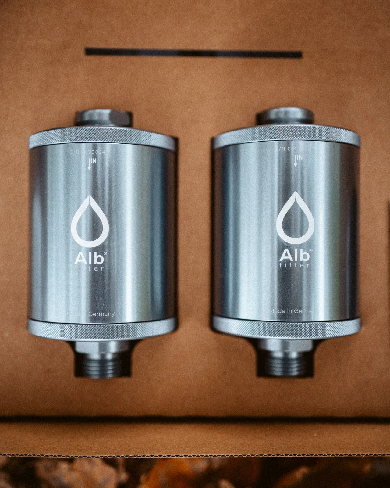 Zwei Aluminium-Wasserfilter in einer Verpackung aus braunem Karton.