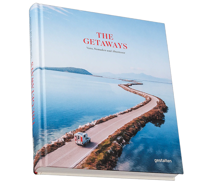 Ein Buch mit dem Titel "The Getaways" zeigt eine Straße, die an einem See entlangführt, mit einem Wohnmobil darauf, vor einem ruhigen Wasser und Bergen im Hintergrund.