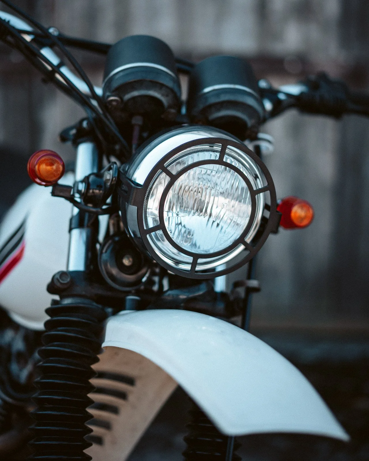 Frontansicht eines weißen Motorrads mit großem Scheinwerfer, Blinker und Vorderreifen.