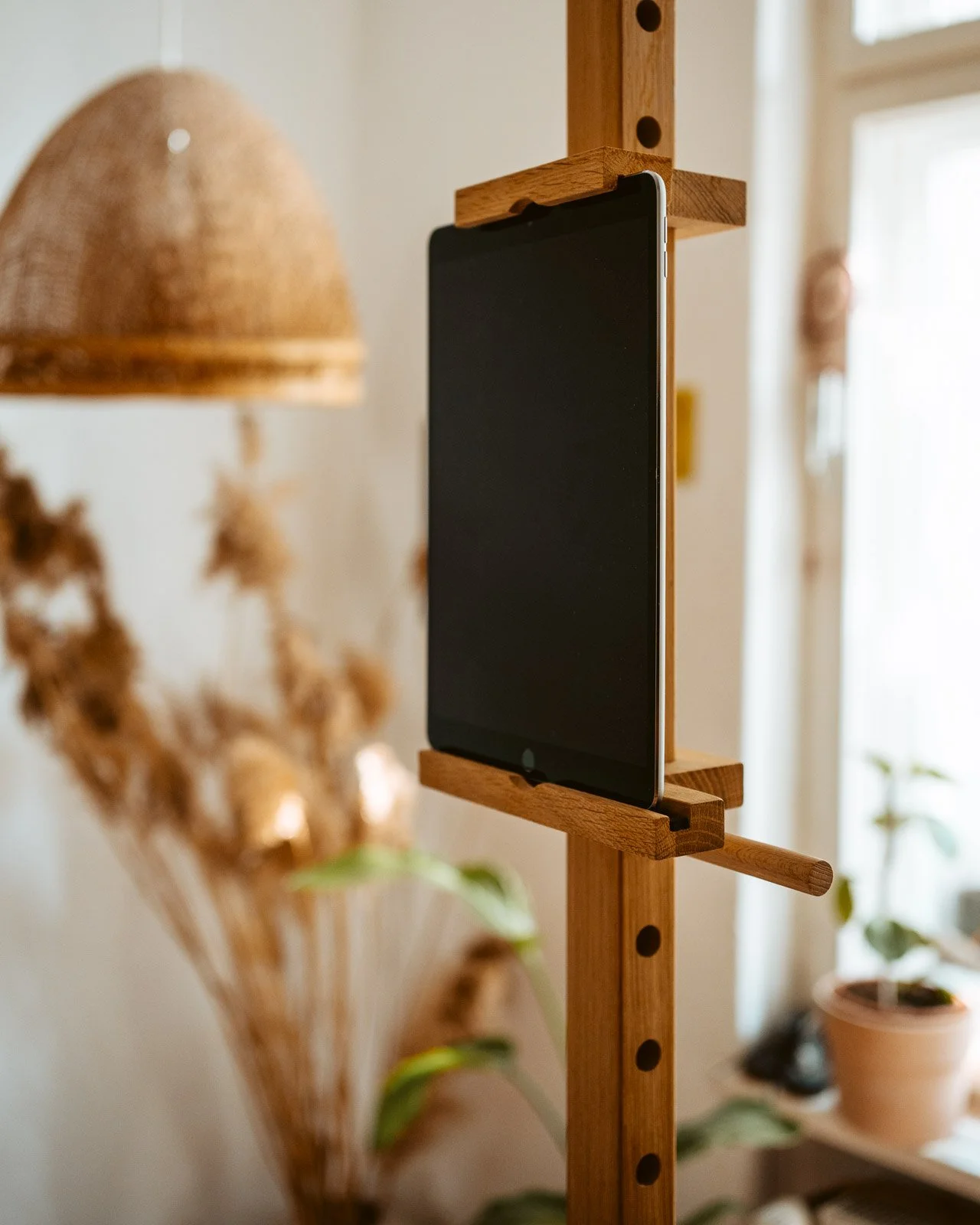 Smartphone ist an einer vertikalen Holzhalterung angebracht, in einem Raum mit Pflanzen und natürlichem Licht.