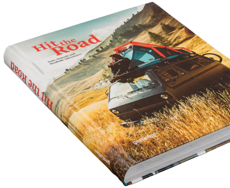 Buchcover mit dem Titel "Hit the Road", zeigt ein Auto auf einer Landstraße mit einer Person, die Sonnenbrille trägt, im veröffentlichten Gebiet. Das Cover hat einen Naturhintergrund mit Hügeln und Wiesen.