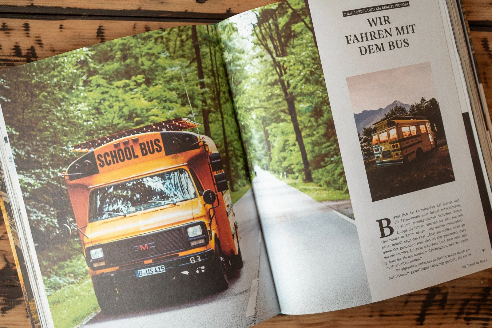 Ein gelber Schulbus fährt auf einer ruhigen Straße durch einen grünen Wald.