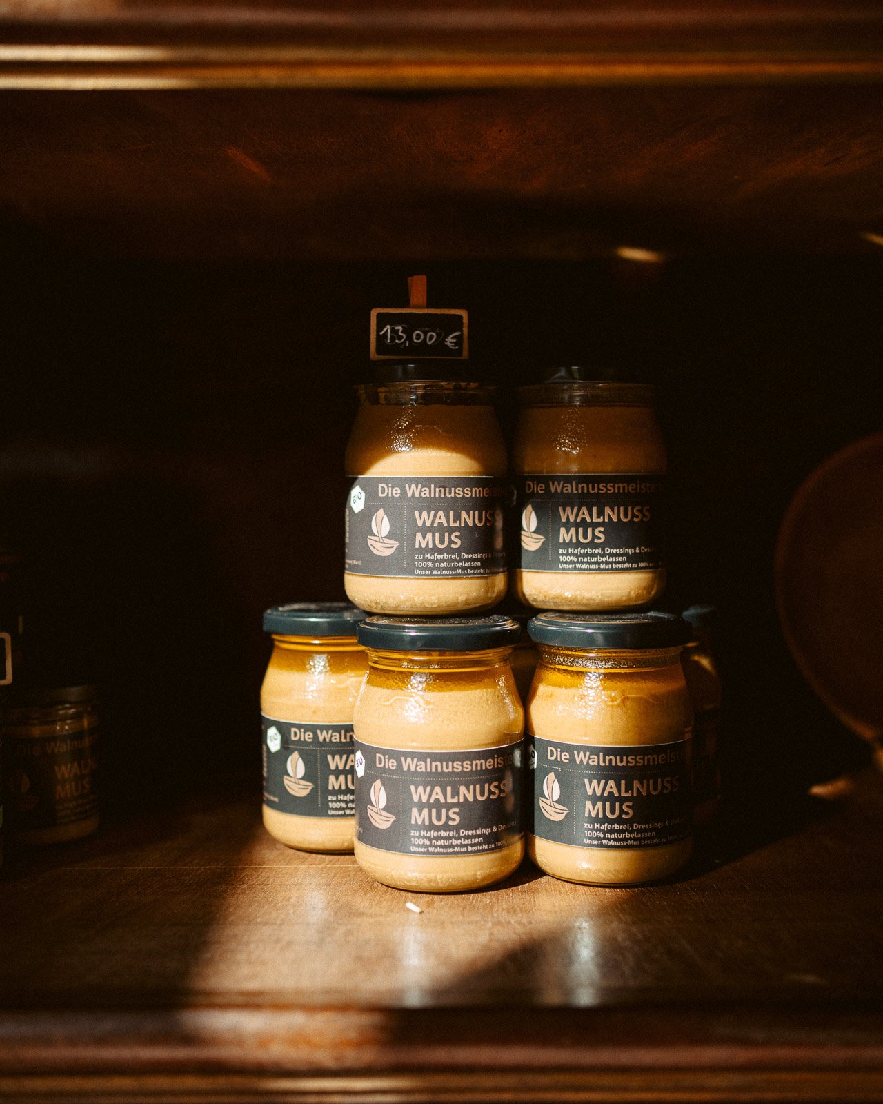 Gläser mit Walnussmus auf einem Holzregal, Preisetikett 13,00 €.