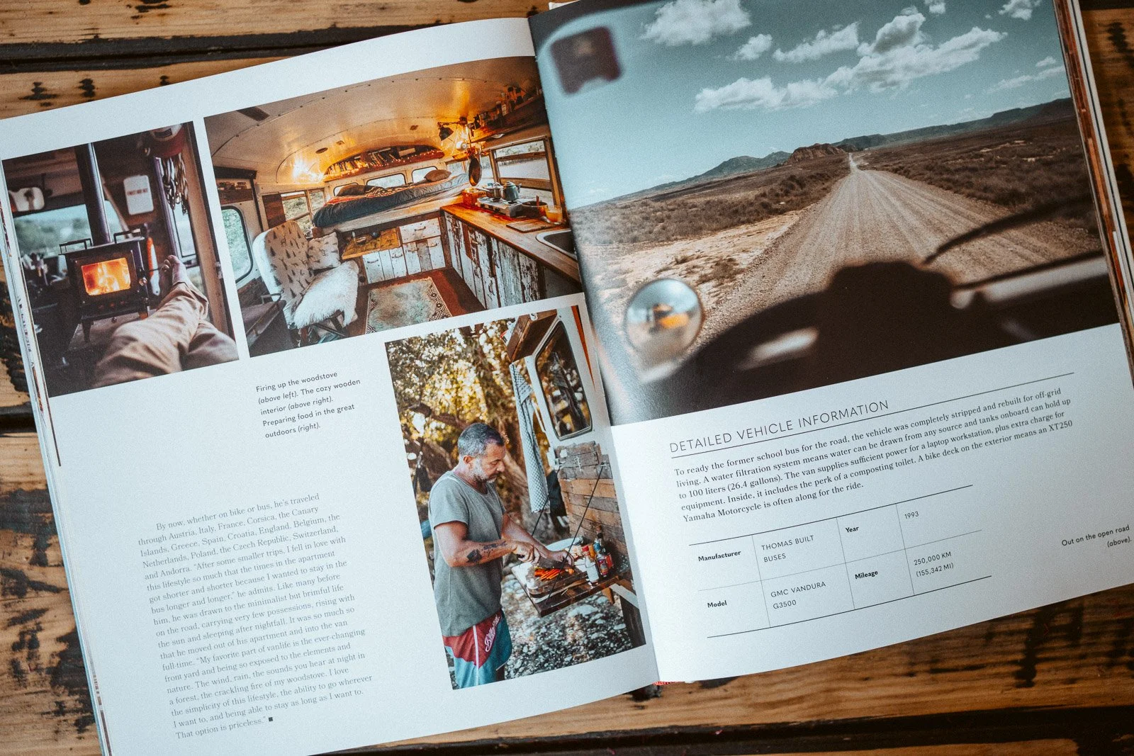 Offener Reiseführer mit Fotos von einem Van-Innenraum, einem Kamin, einer Person beim Grillen im Freien und einer 4x4 Offroad-Straßenaufnahme.