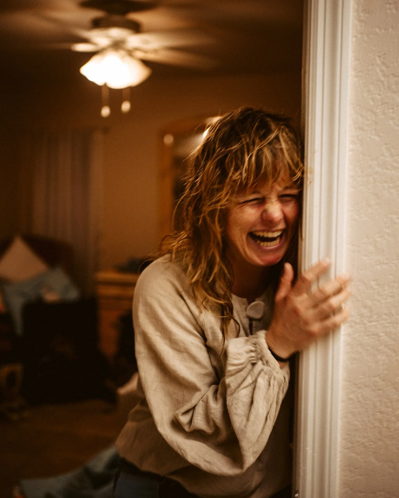 Frau, die vor einer Wand steht und schreit, lachend, im Haus.