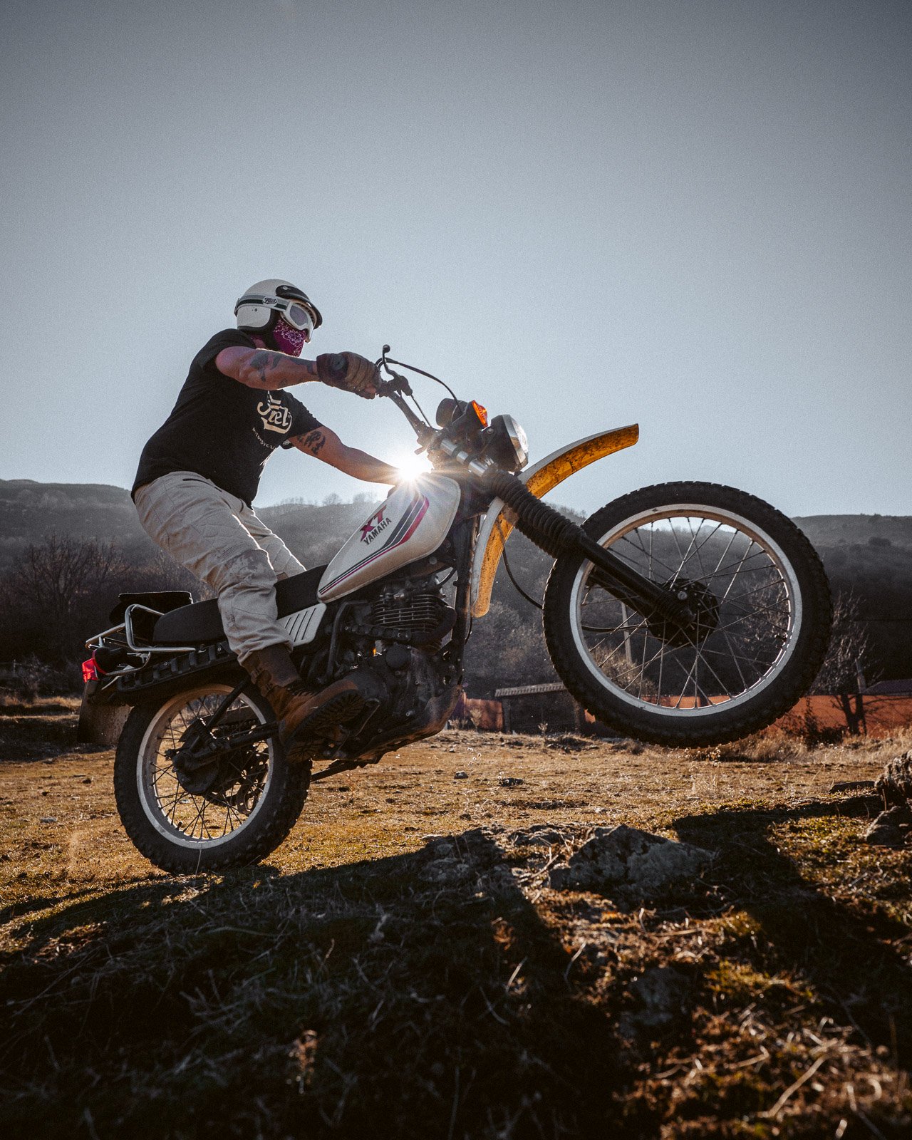 Ein Mensch fährt mit einer Dirt Bike in einem offenen Gelände bei Sonnenuntergang.